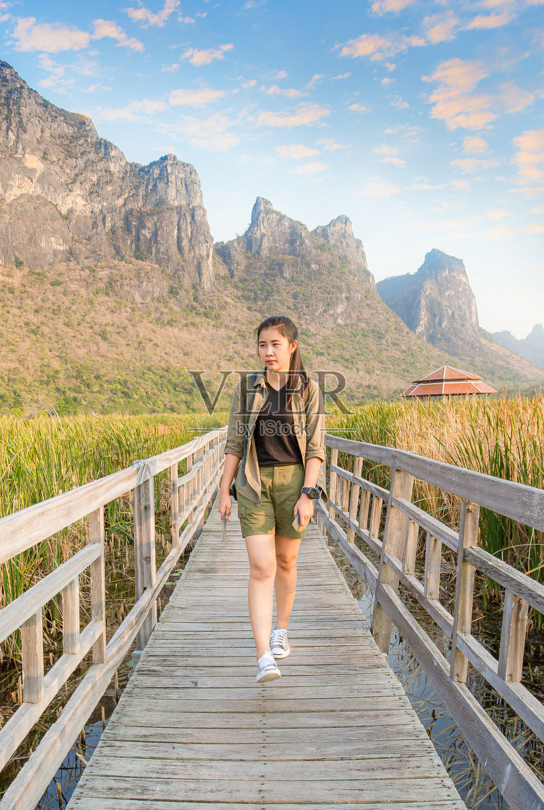 自由旅行的女人站在日出的海滨山峰，举起双臂，享受美丽的大自然和欢呼的年轻女性背包客照片摄影图片