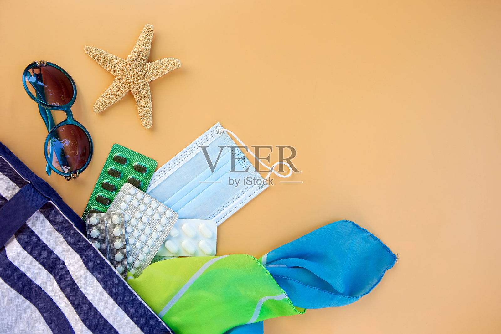 沙滩包，妇女配件，药丸，注射器和保护性医疗口罩在米色的背景。前视图。照片摄影图片