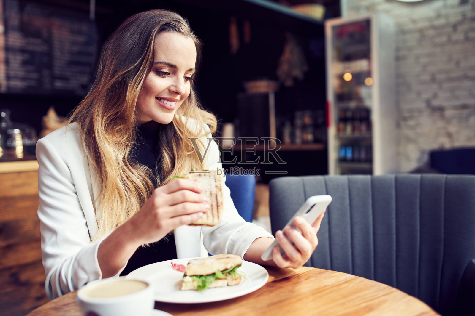美女在咖啡馆用手机吃早餐照片摄影图片
