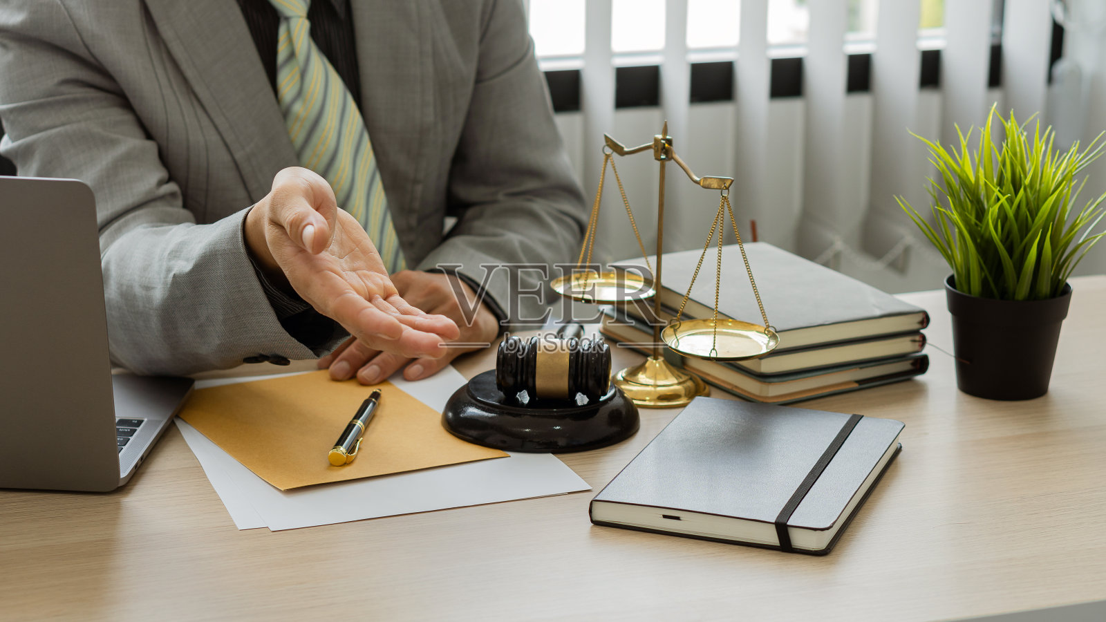 在办公室办公桌前工作的男律师强调法官的天平和锤子，并在他们面前放上笔记本电脑。照片摄影图片