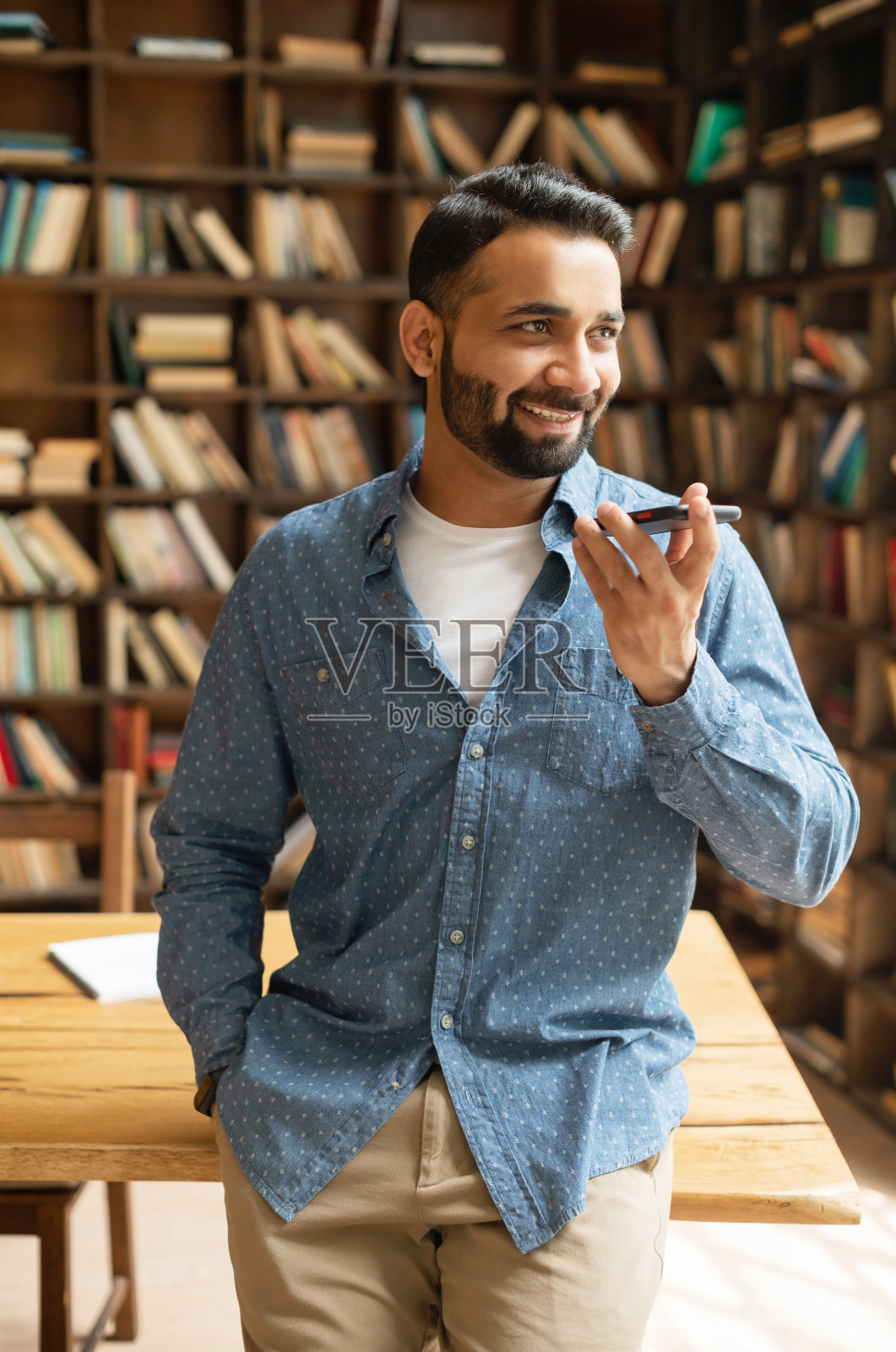 一名印度男子穿着时髦的便服，正在录音和发送语音信息照片摄影图片
