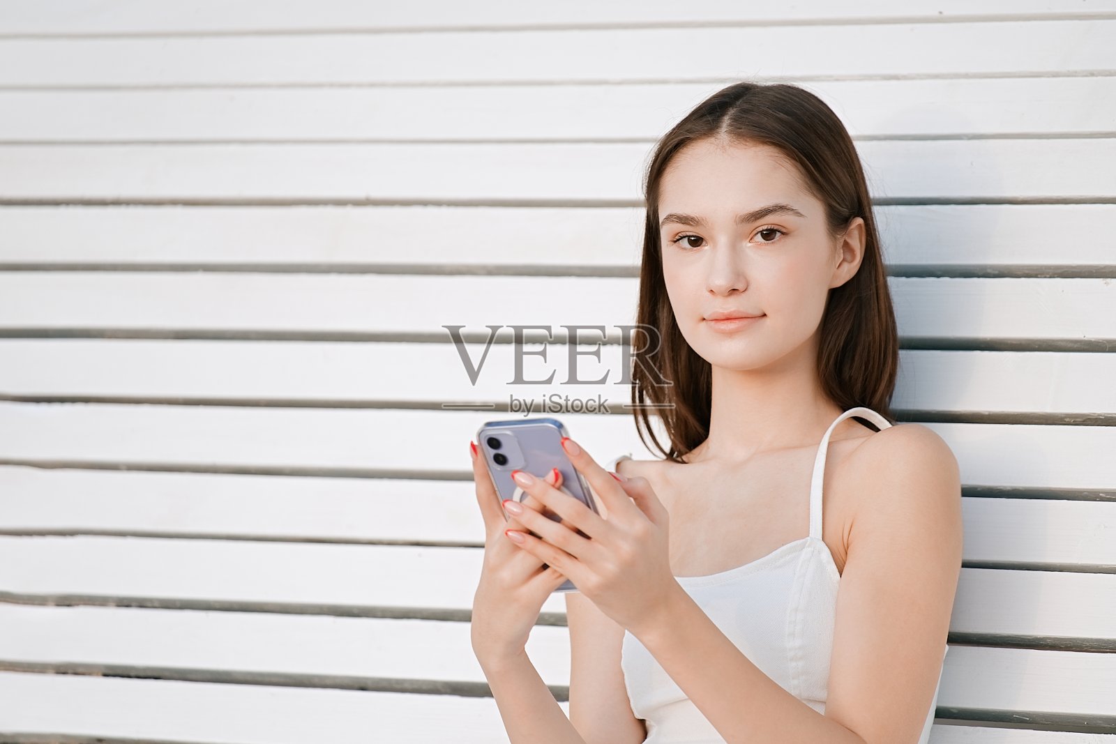 女孩坐在长椅上用手机聊天照片摄影图片