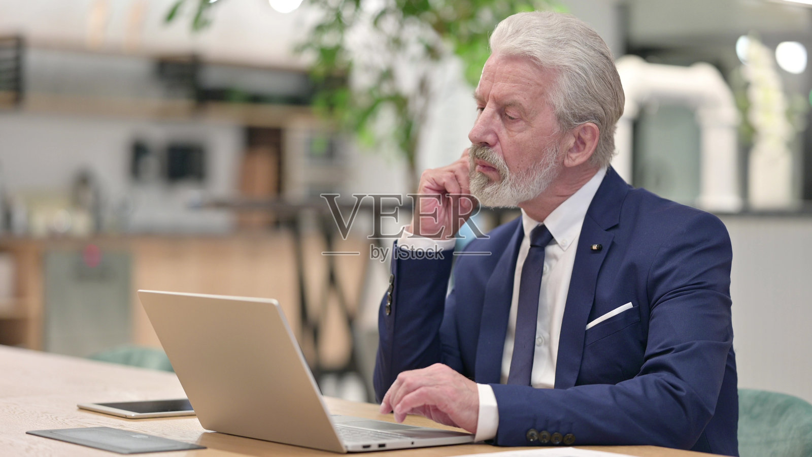 老商人在笔记本电脑上思考和工作照片摄影图片