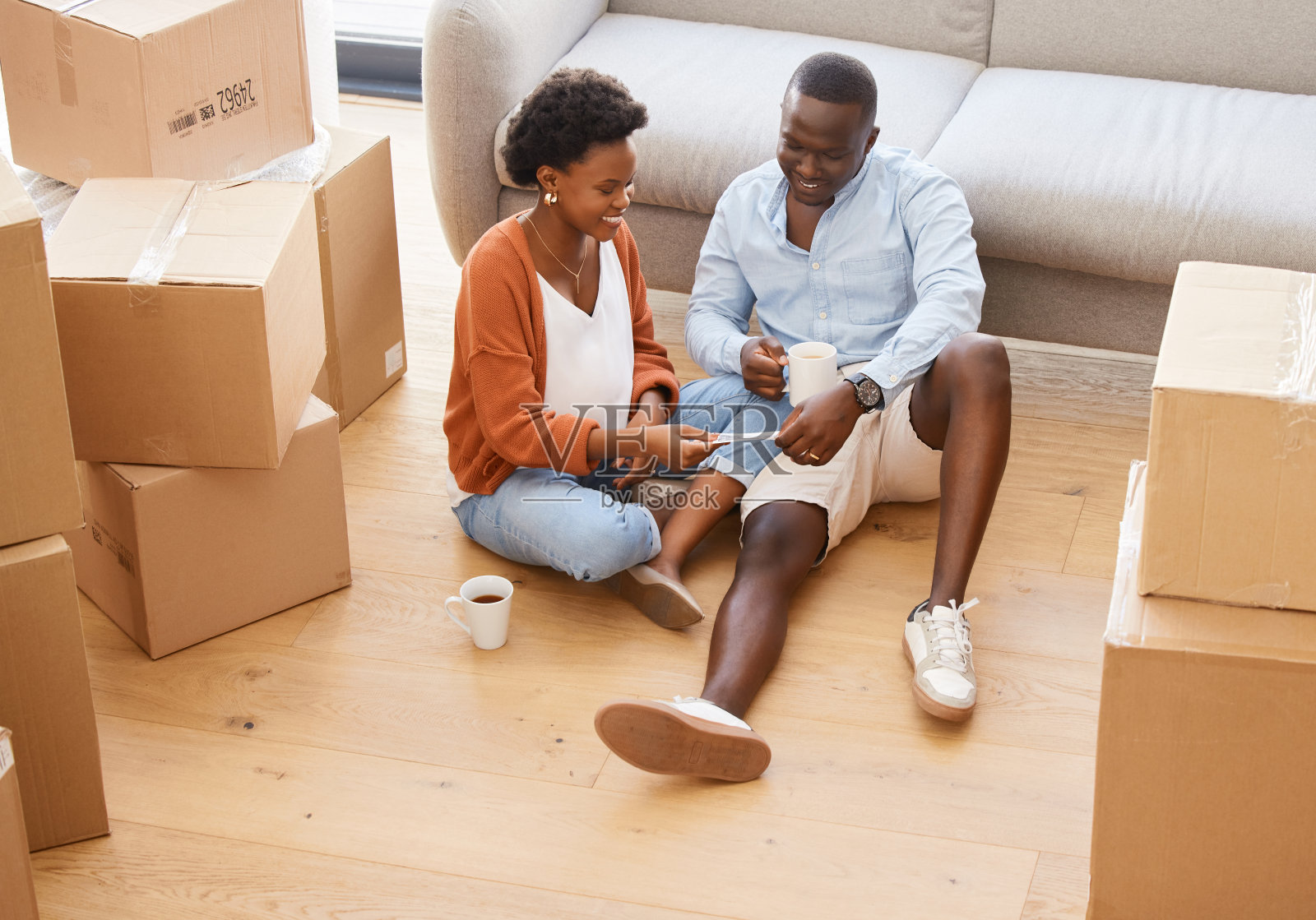 一对年轻夫妇坐在地板上，看着家里的超声波照片照片摄影图片