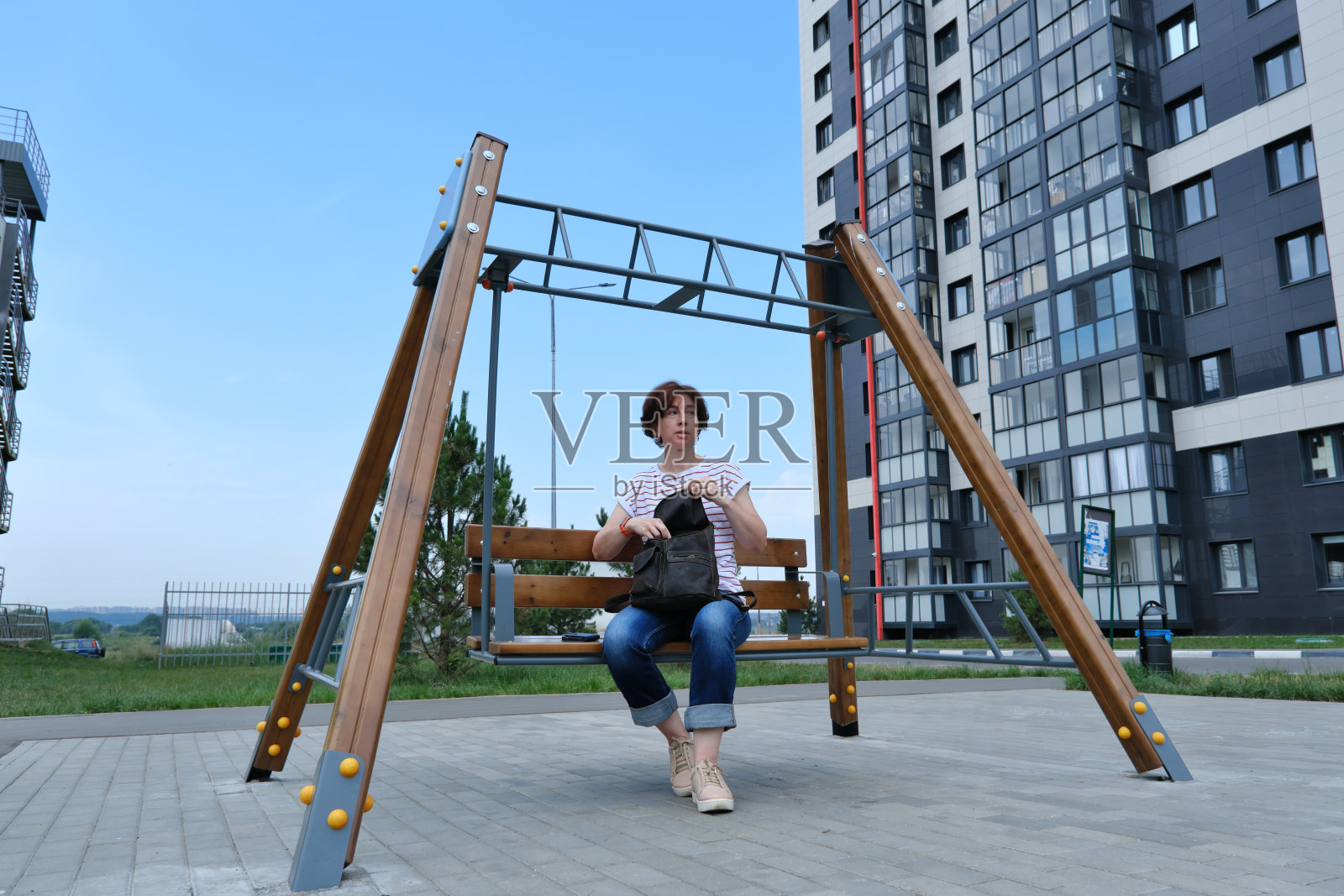 一个女人坐在摇摆的长凳上，打开背包照片摄影图片