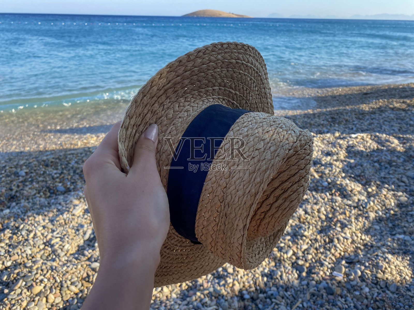 在沙滩上拿着一顶草帽照片摄影图片