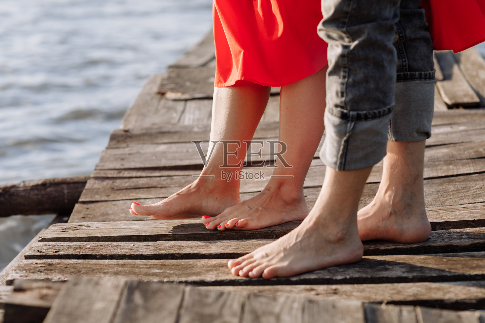 剪短的照片，一对年轻情侣结婚了，丈夫和妻子，手牵手在湖边的木桥上。一对夫妇站在码头上的后视图。降低一半。放置文本和设计。关闭了。照片摄影图片
