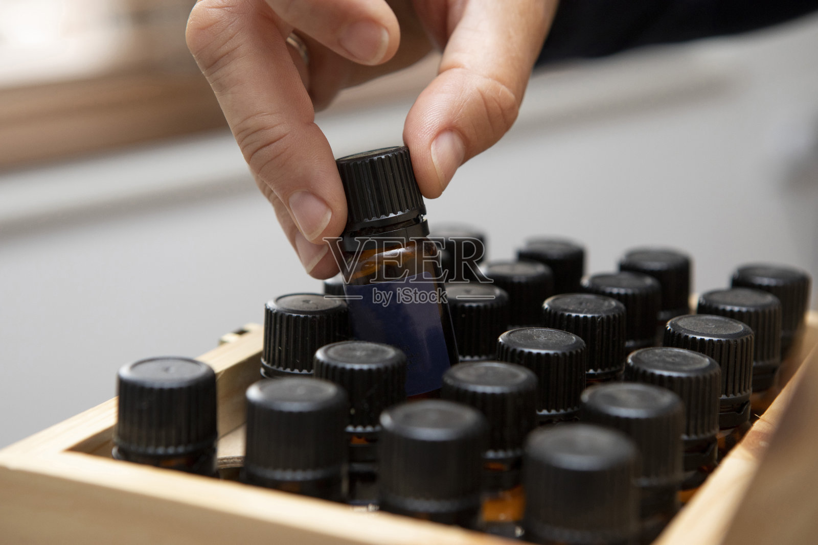 女性的手从一个木盒子里挑选一瓶按摩油的特写照片摄影图片