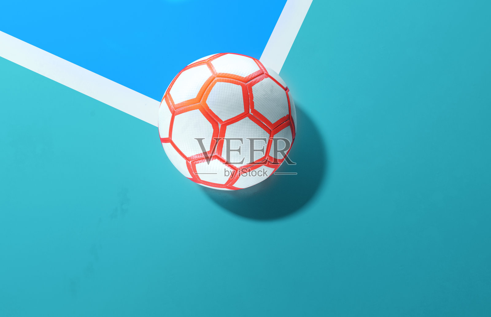 一个白色橙色的五人制足球特写在一个明亮的蓝色足球场背景的角落里照片摄影图片