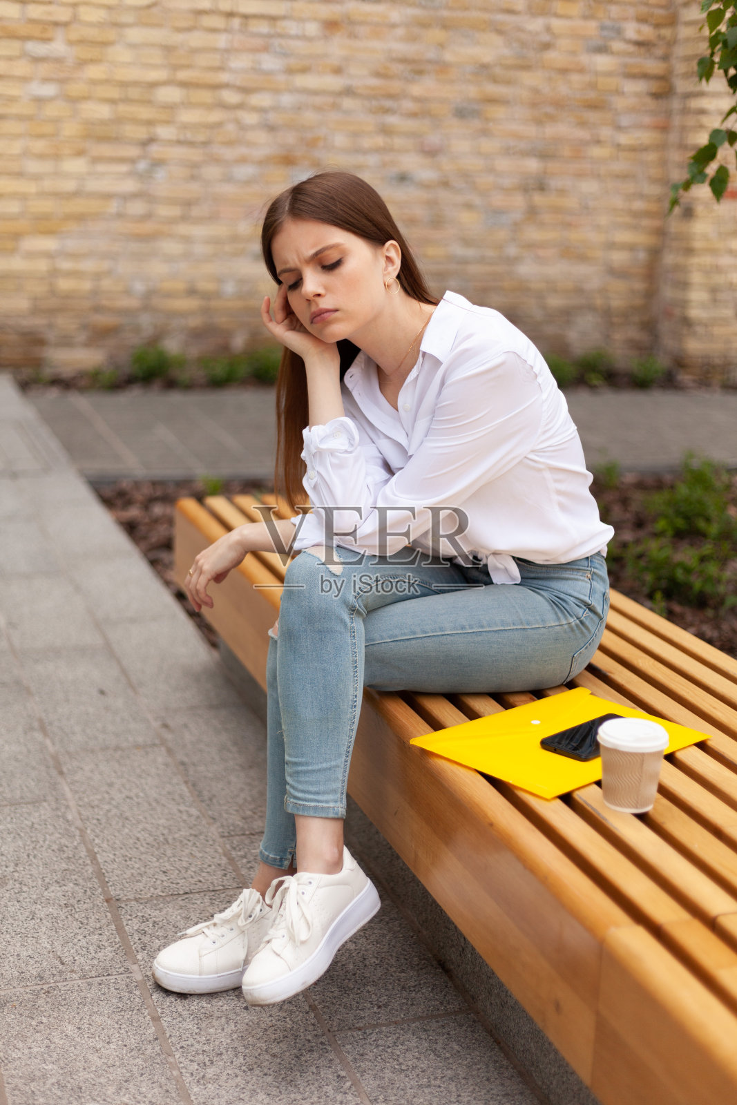 心烦意乱的年轻女子坐在户外。头痛,倦怠照片摄影图片