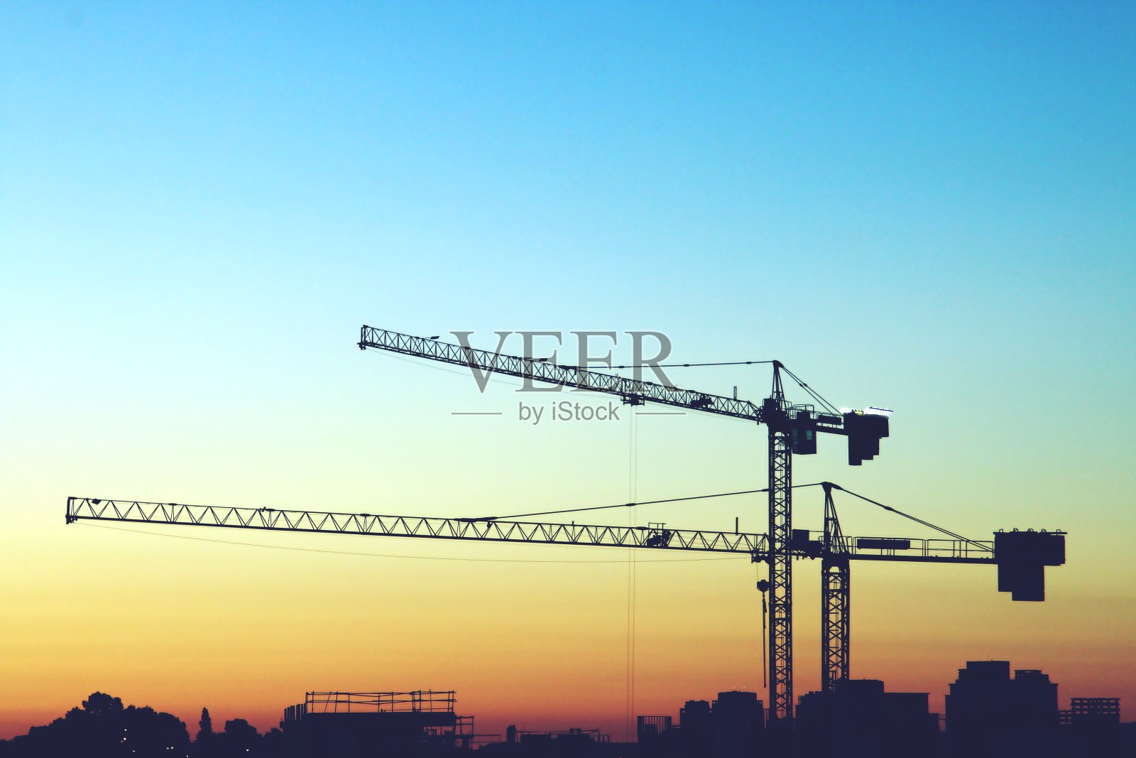 日落时建筑塔吊。照片摄影图片