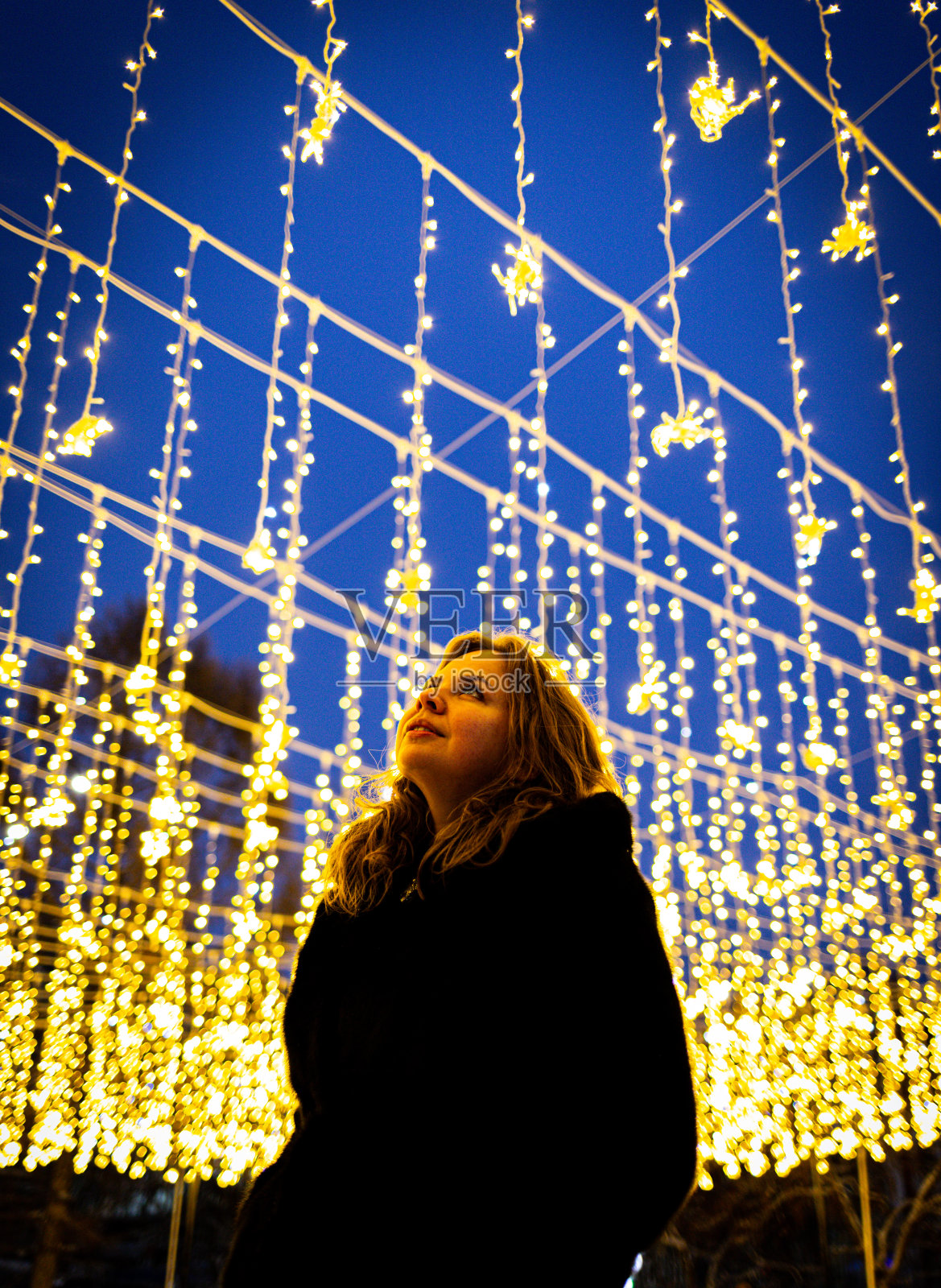 一个女孩的肖像在许多花环灯的背景下照片摄影图片