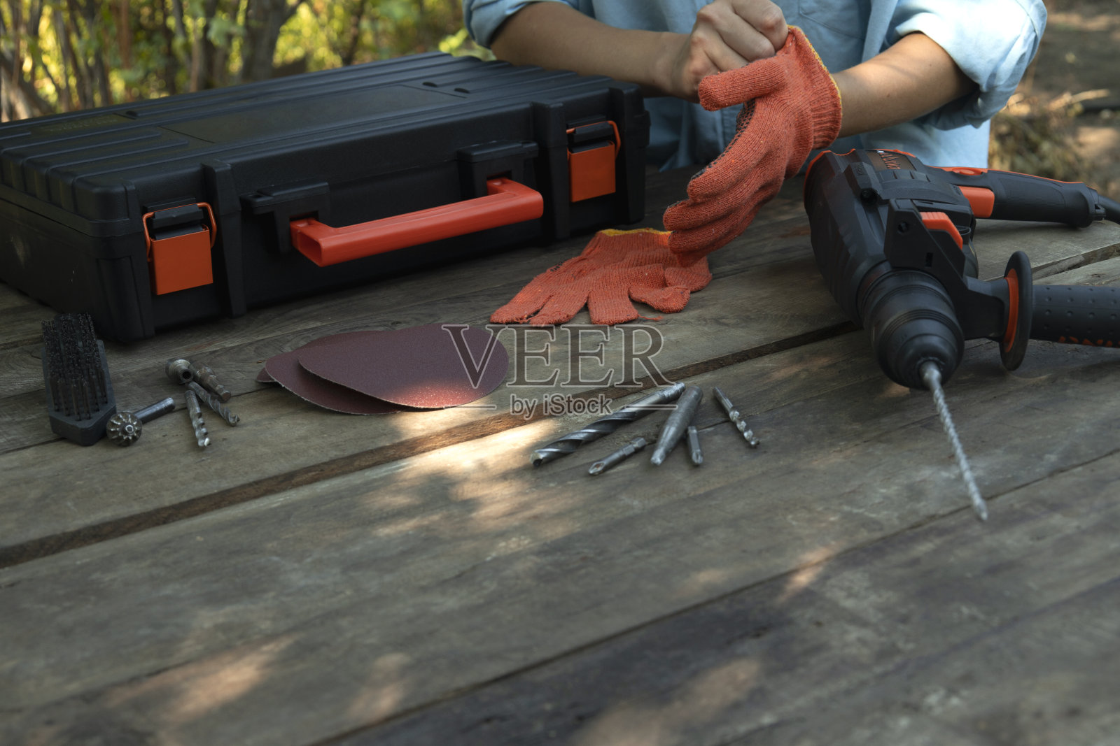 一套钻头，铁锤钻，木桌上的一层砂纸。工人在室外维修前戴手套。空的空间照片摄影图片