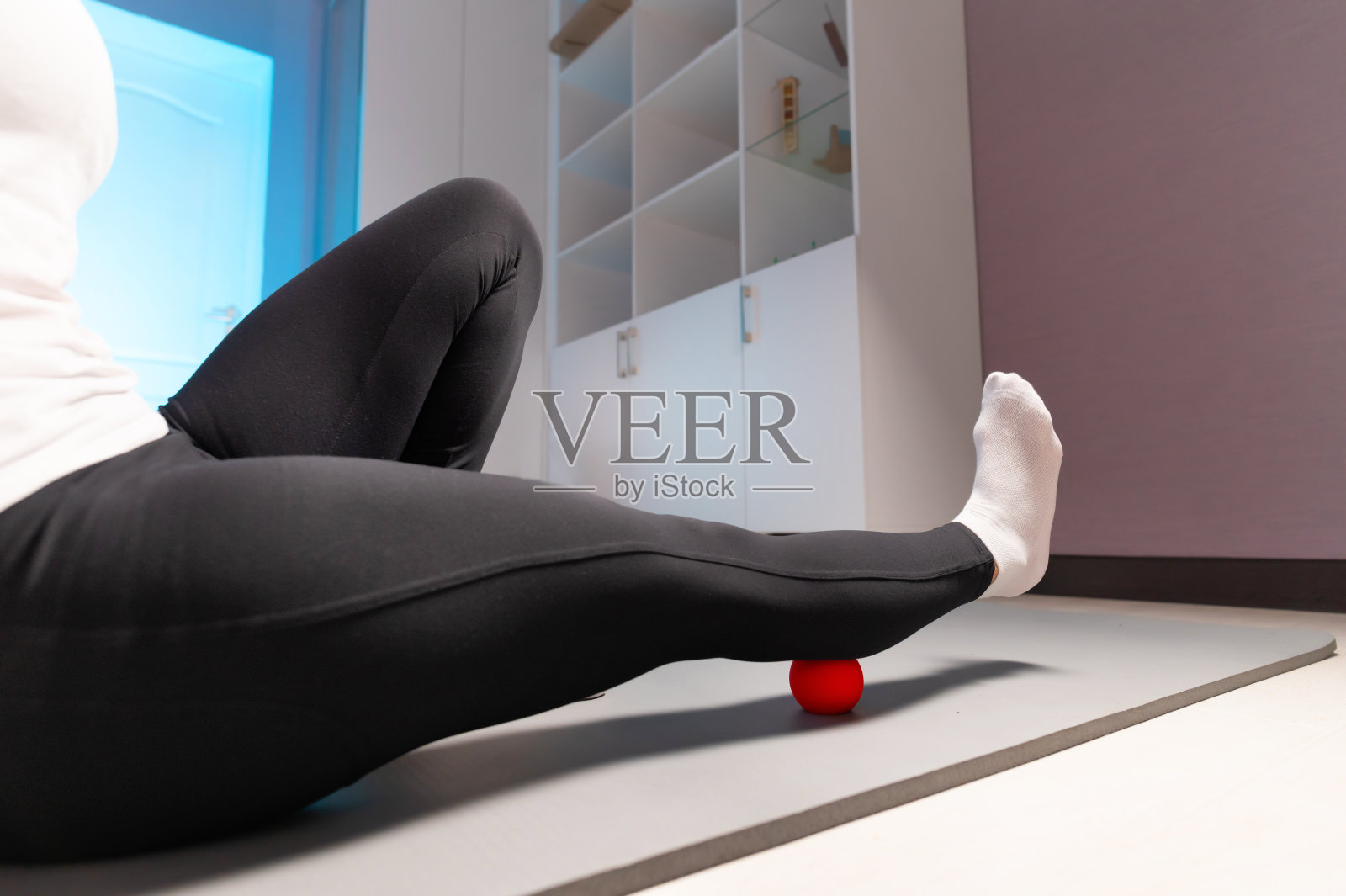 特写的运动妇女在室内使用按摩球自我按摩。没有按摩师的肌筋膜按摩。消除腿部肌肉疼痛照片摄影图片