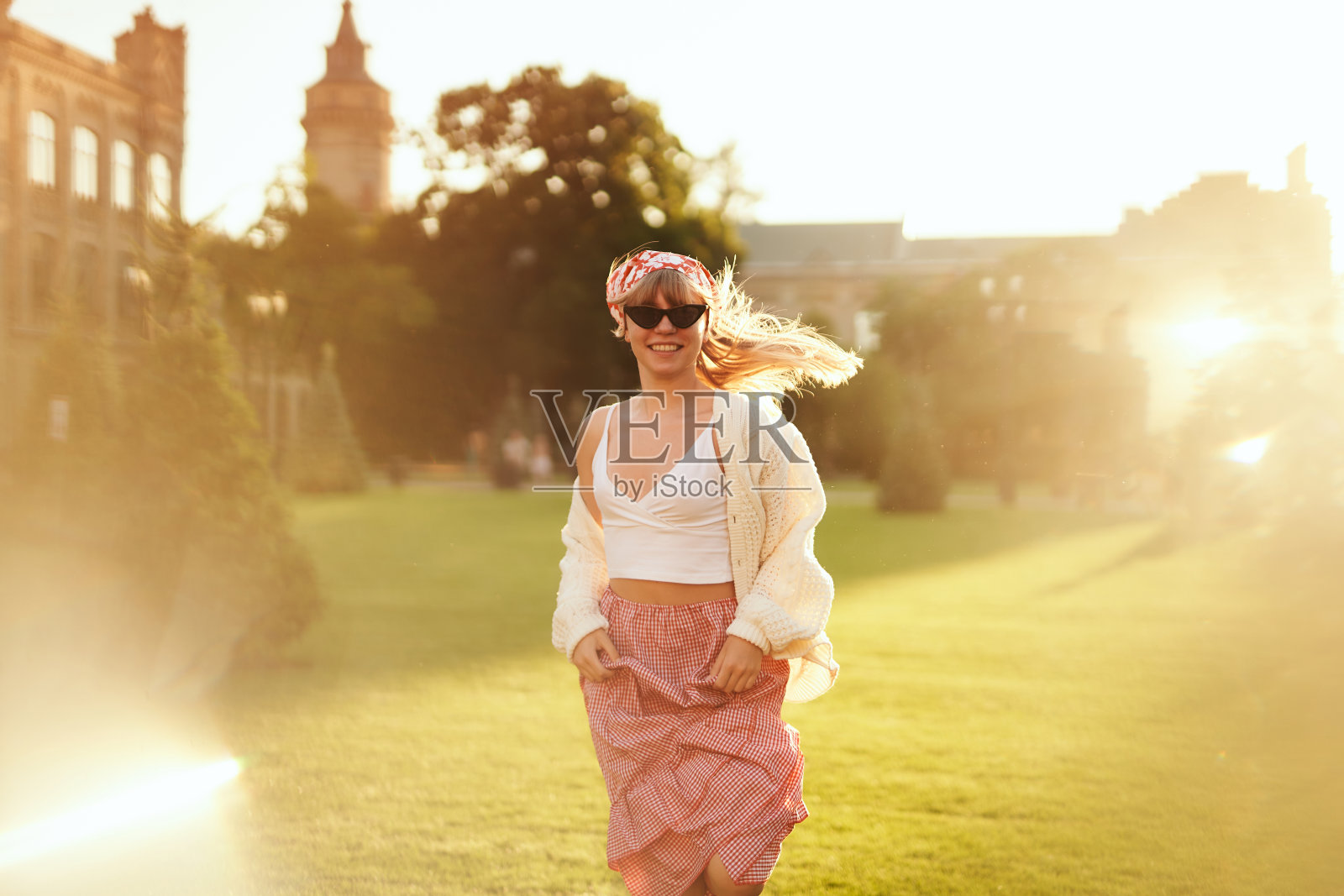 黄昏时分，穿着连衣裙、头巾和毛衣的女人在公园里跑步照片摄影图片