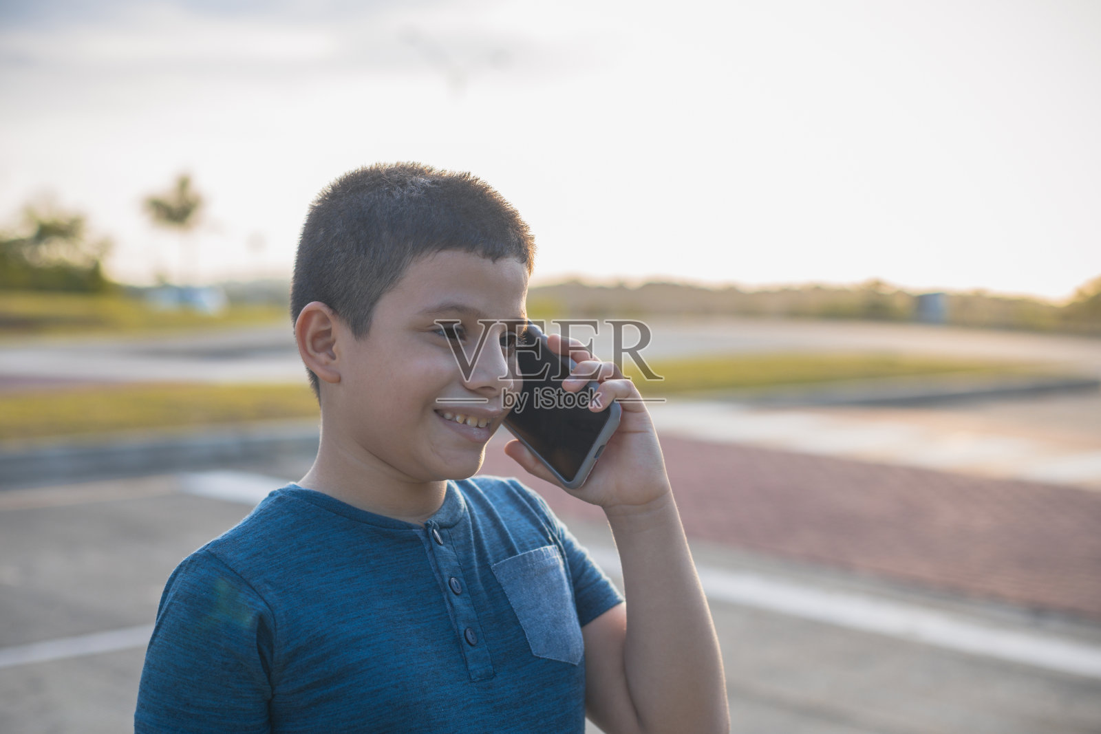 一个拉丁裔男孩在日落时分的大街上打电话照片摄影图片