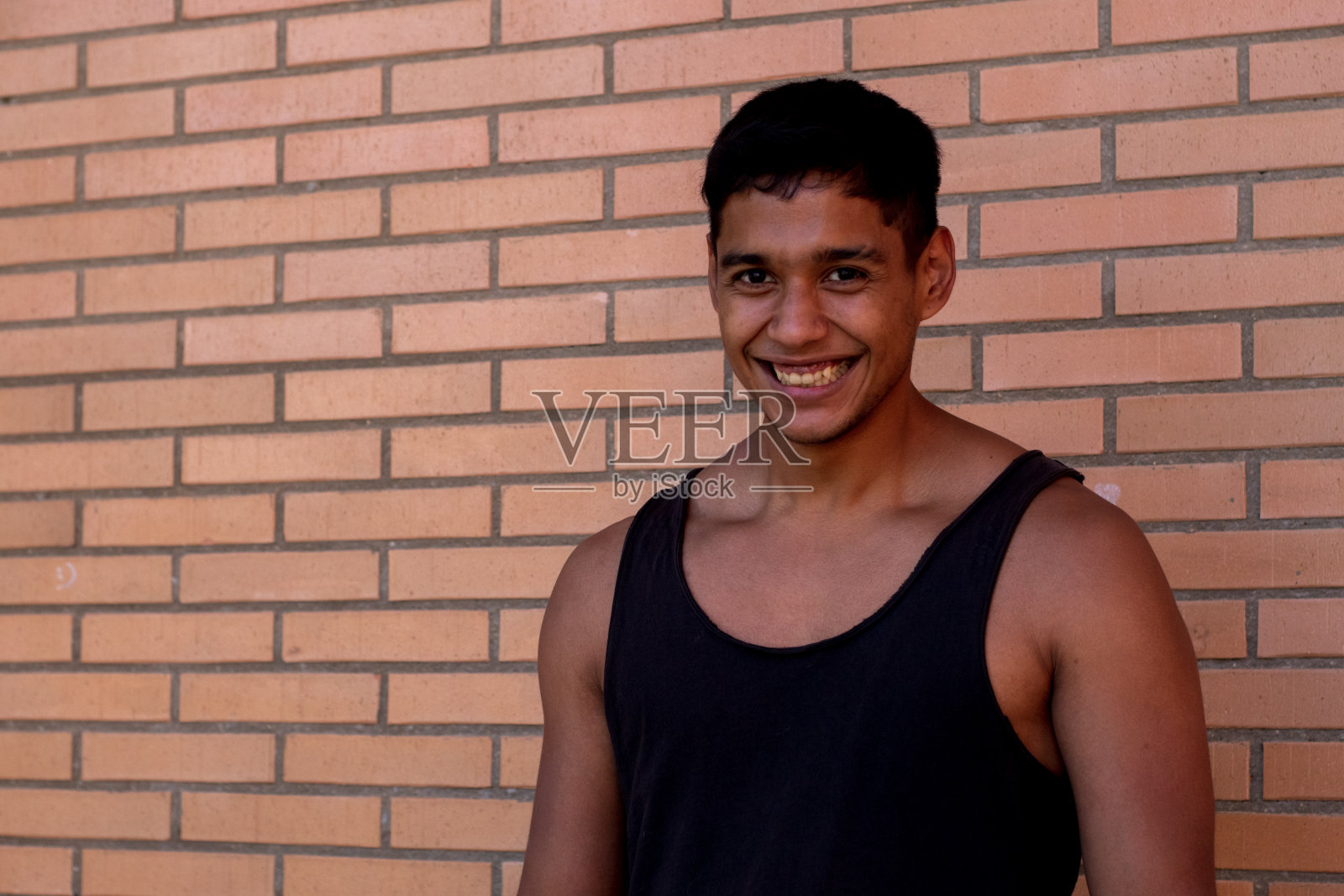 一幅拉丁裔运动员穿着黑色背心在街上微笑的肖像照片摄影图片