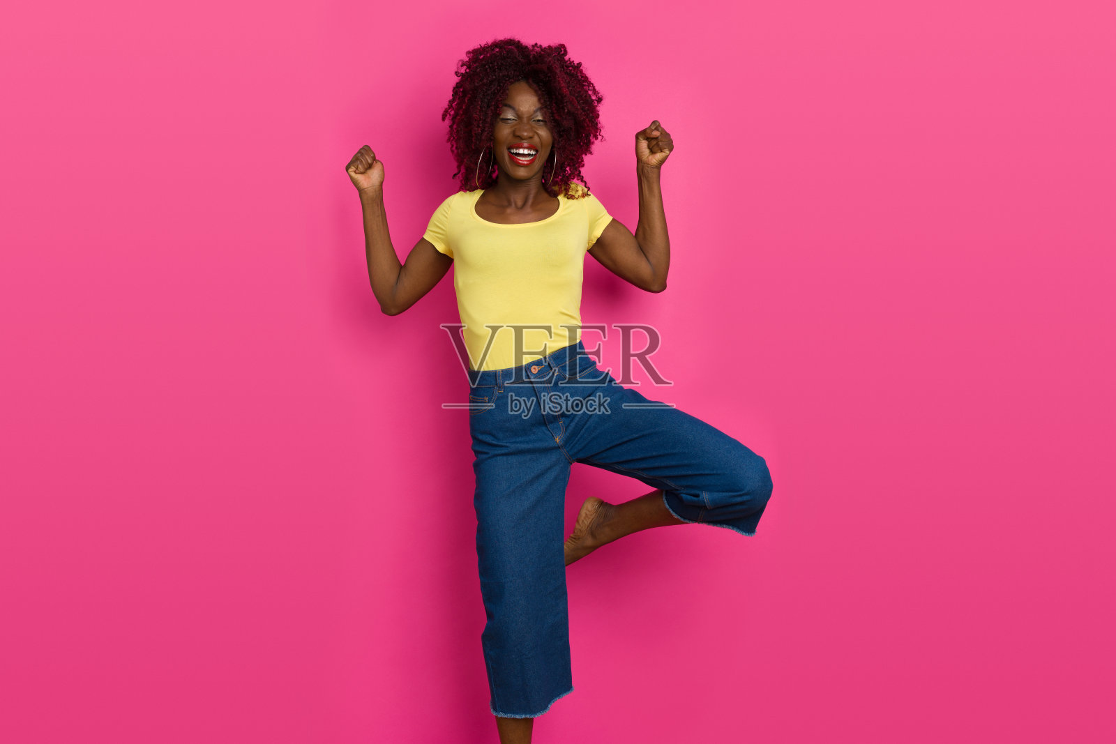 年轻的黑人女子单腿站立，笑着照片摄影图片