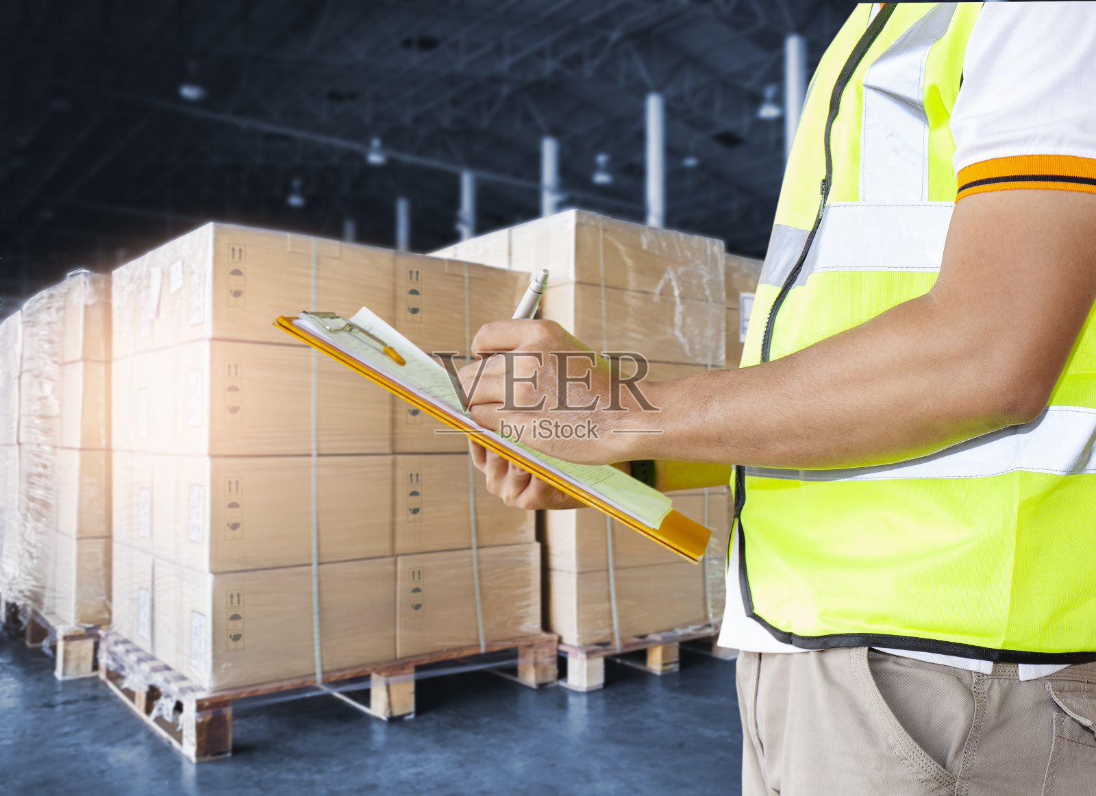 仓库工人拿着剪贴板在仓库进行库存管理。检查库存包装盒。照片摄影图片