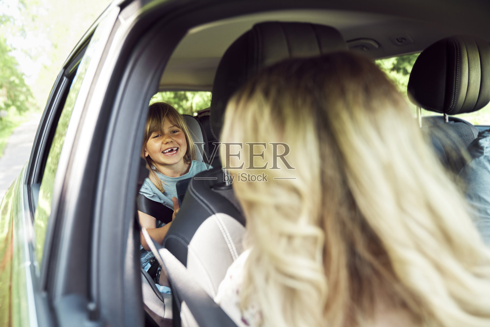 小女孩微笑着和她妈妈在车里亲热照片摄影图片