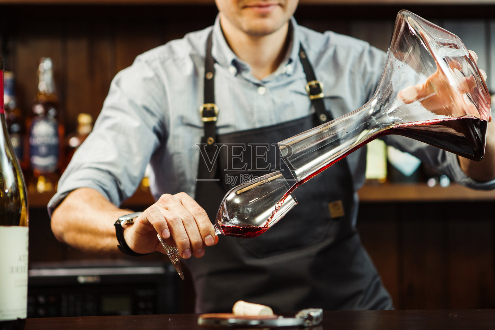侍酒师将酒从碗中倒入玻璃杯中。男服务员照片摄影图片