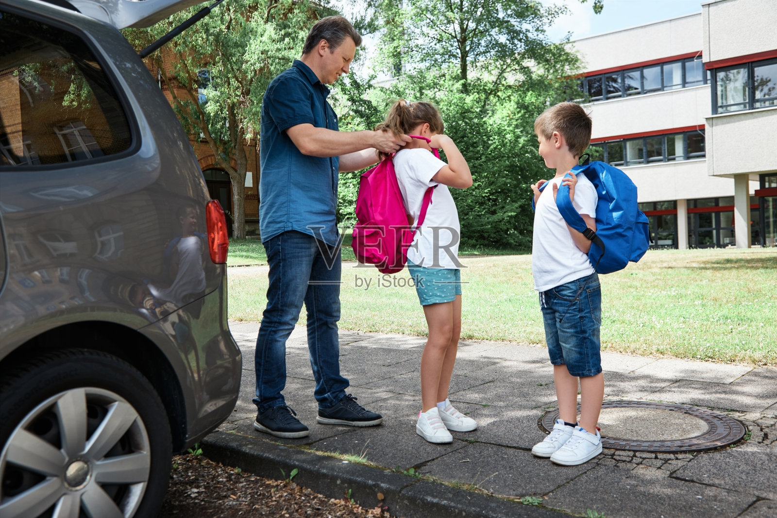 父亲送孩子们上学，然后帮女儿装上背包。这是学年开学日的开始。回到学校照片摄影图片