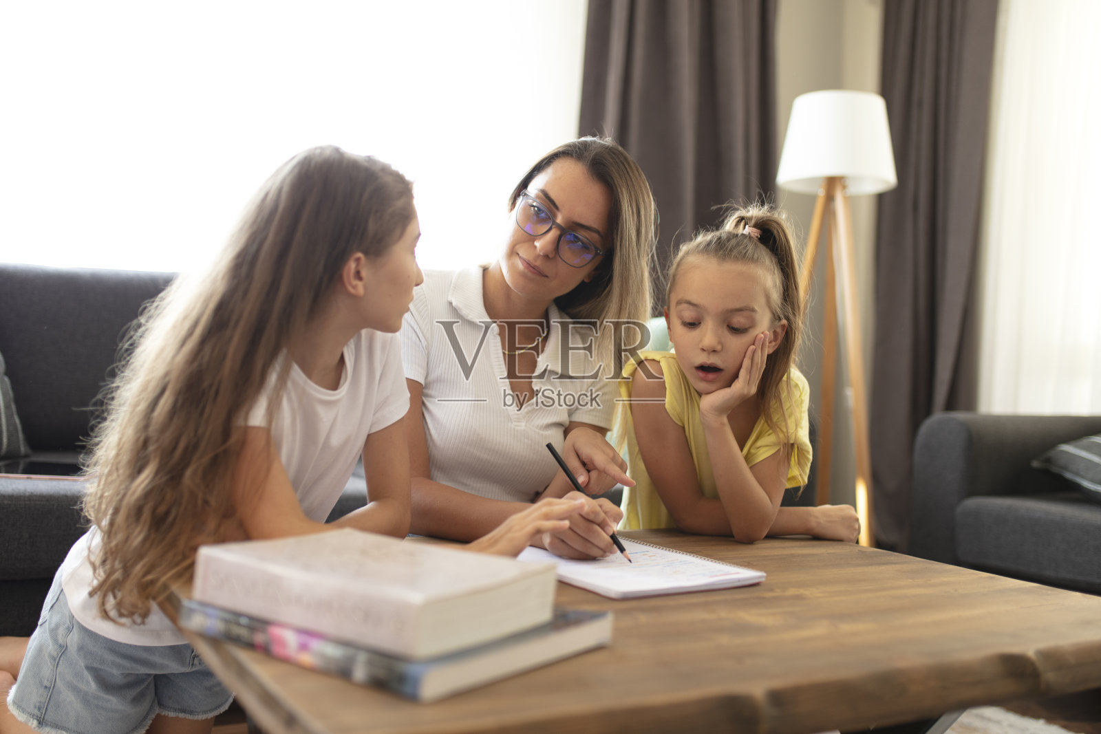 母亲帮助女儿做作业。照片摄影图片