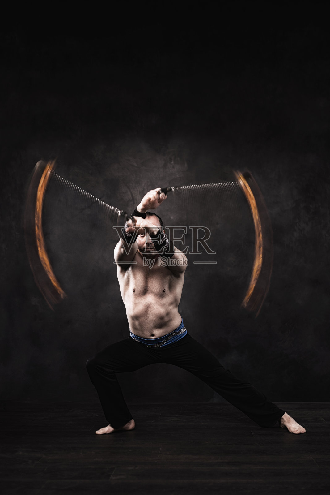 在摄影棚里表演火表演的杂技演员。照片摄影图片