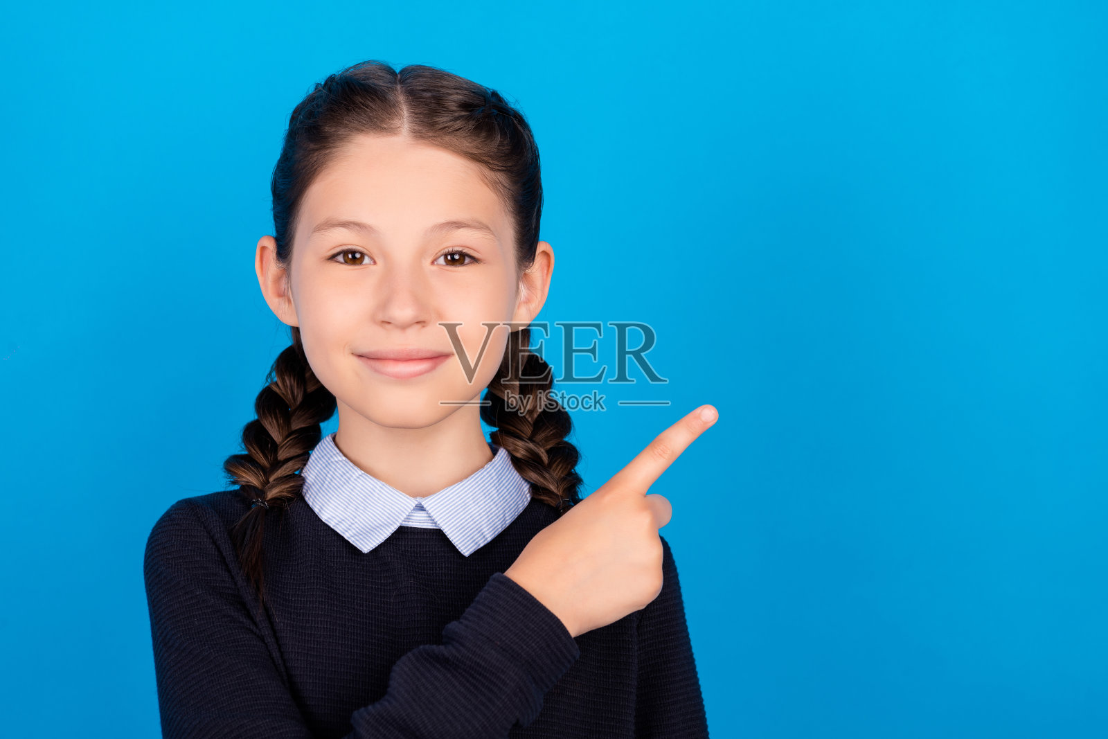年轻开朗快乐积极的小女孩指指点点空卖孤立在蓝色背景上照片摄影图片