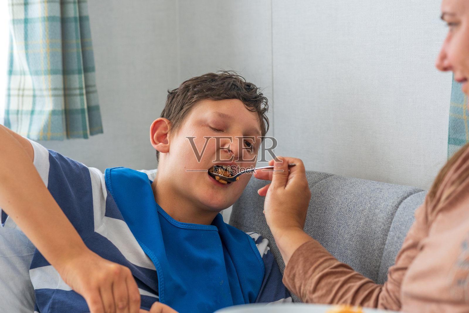 残疾部分失明的男孩由母亲喂养照片摄影图片