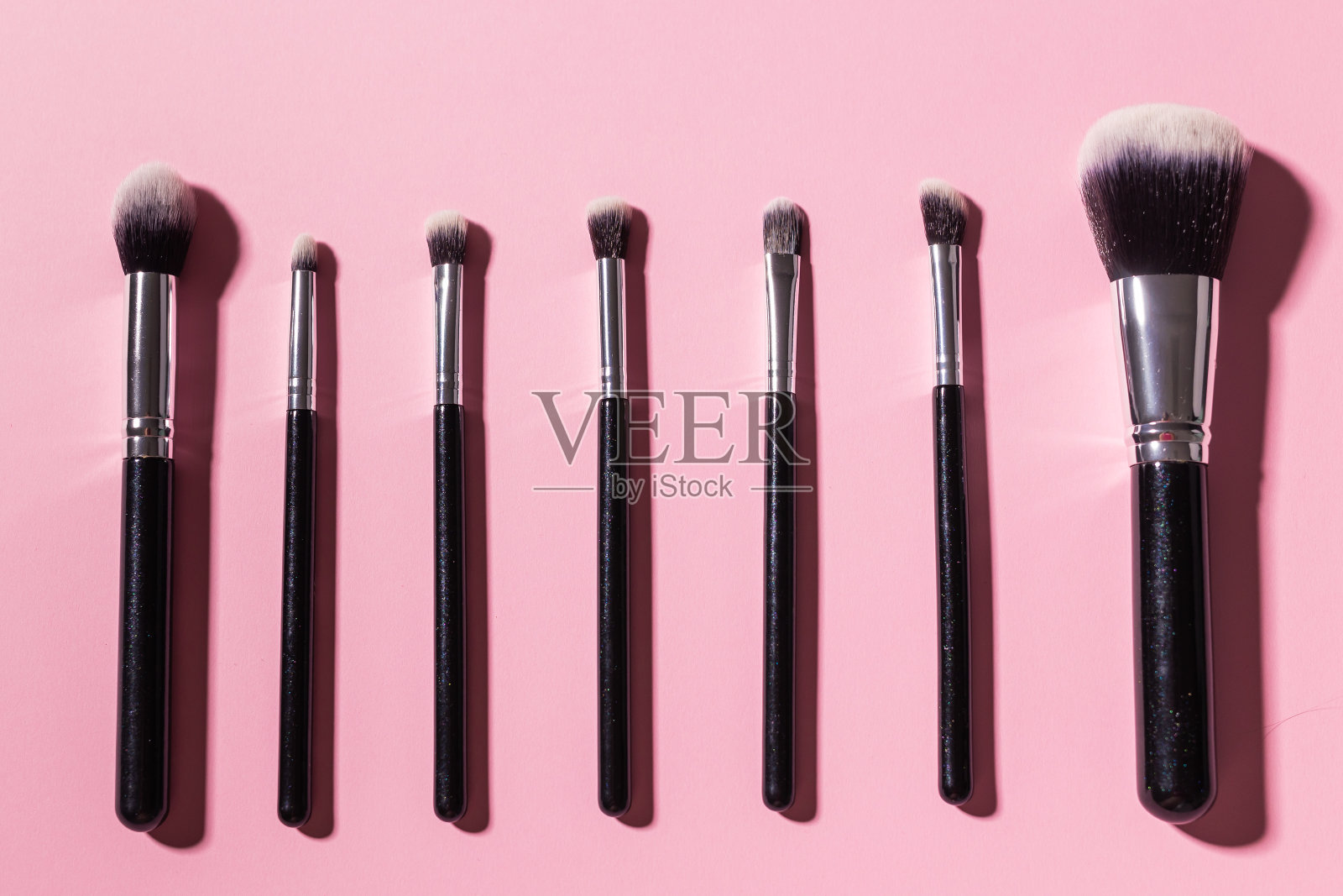 各种化妆刷粉红色背景，俯视图。化妆品和美容概念。照片摄影图片
