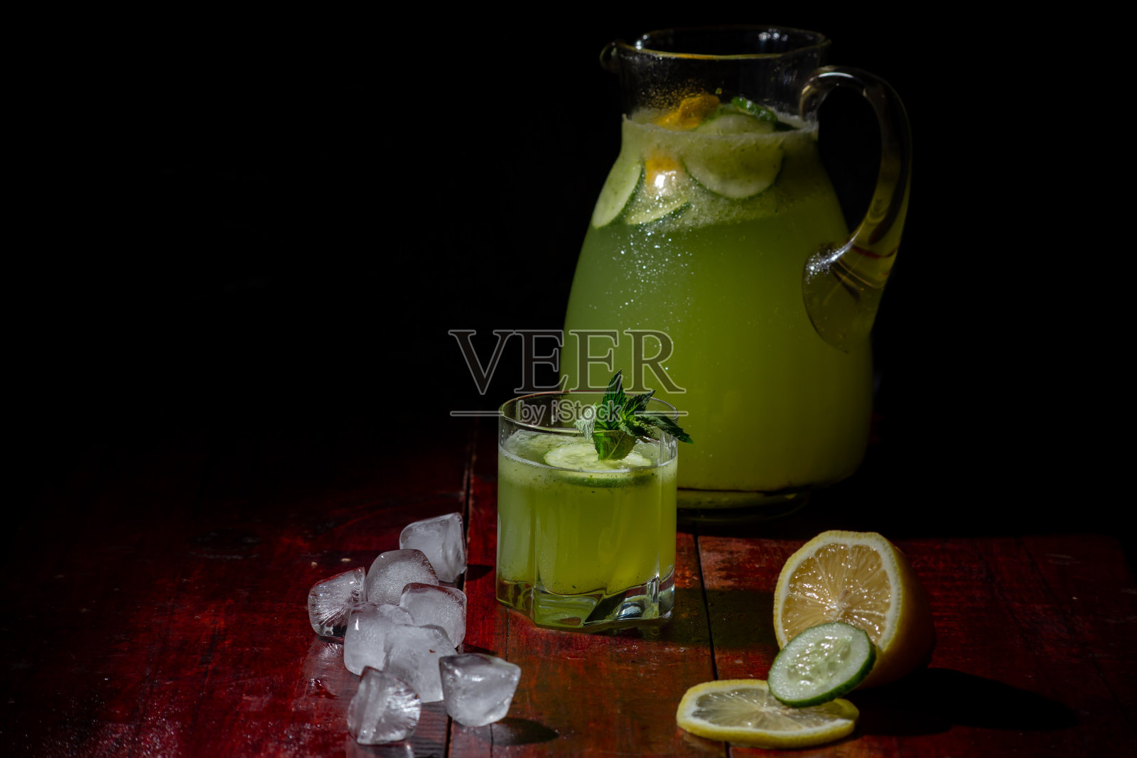 一杯新鲜的黄瓜柠檬水放在桌上，还有薄荷和冰块照片摄影图片