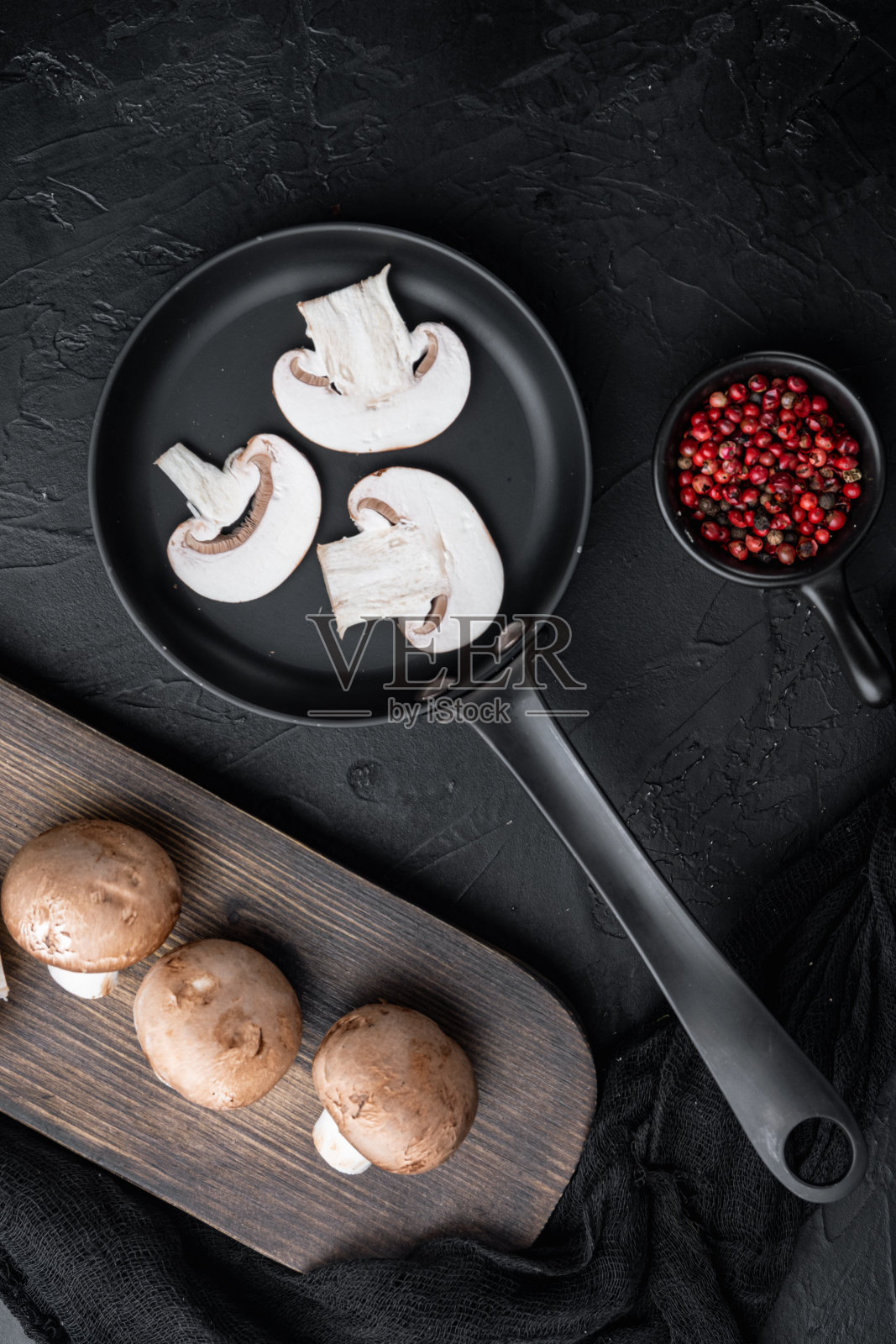 皇家香菇全放在铸铁煎锅中，在黑色背景下，俯视图平铺照片摄影图片