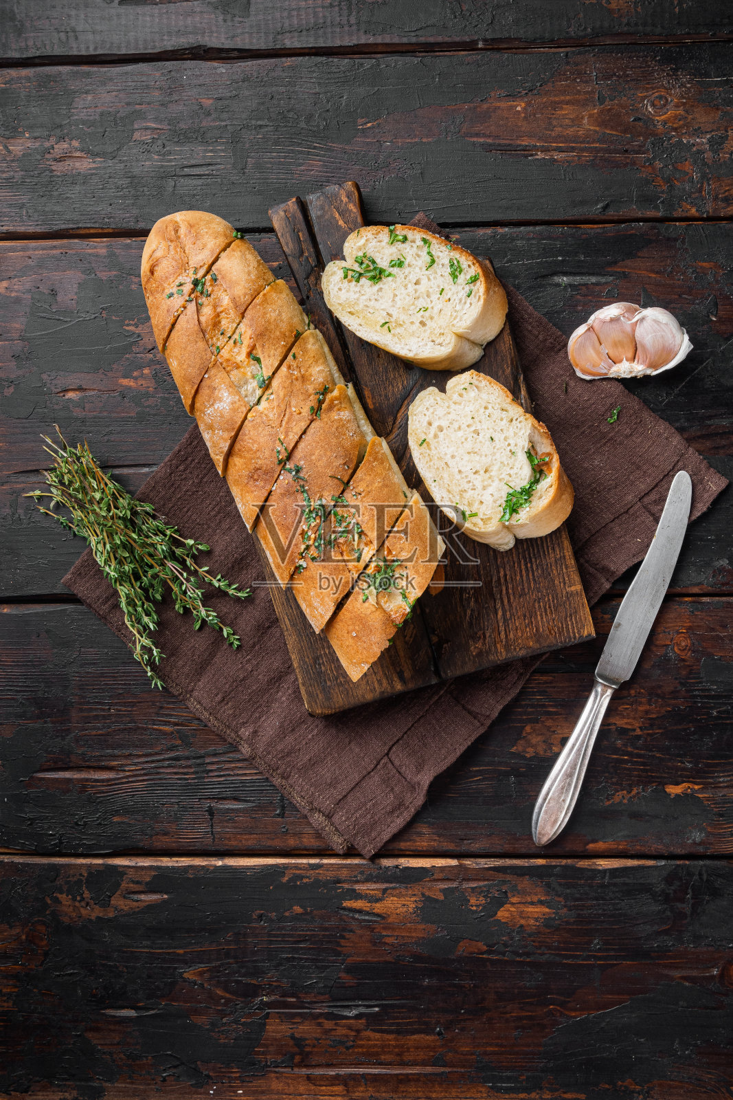 烤面包与大蒜和香草，在旧的深色木桌背景，俯视图平躺，复制空间的文字照片摄影图片