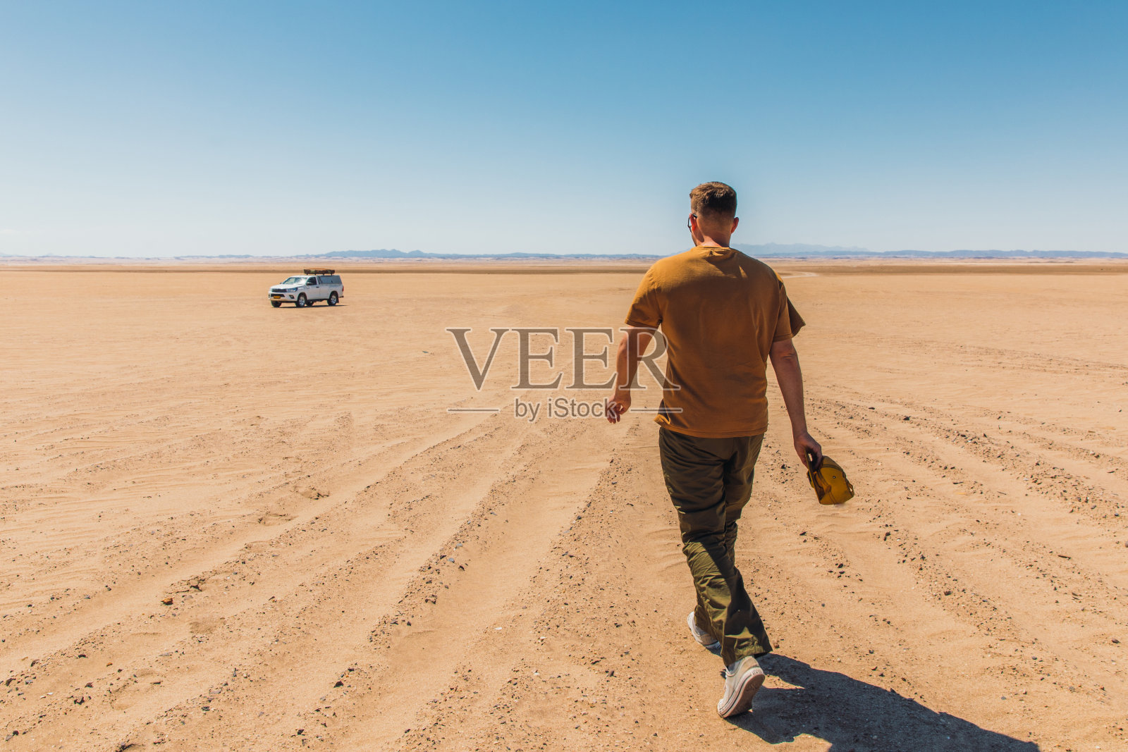 一名旅行者穿过纳米比亚的沙丘走向他的露营车照片摄影图片