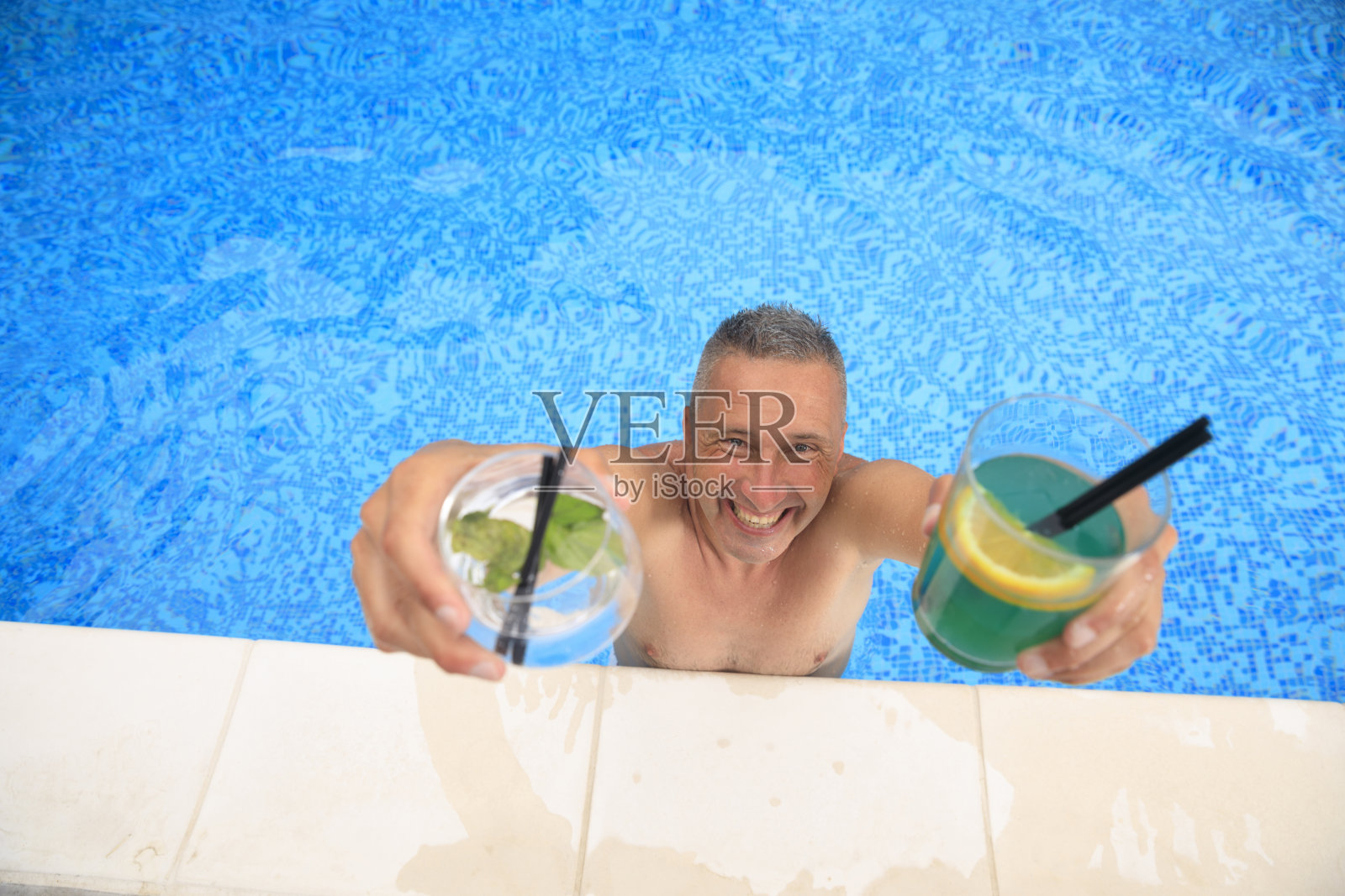 夏天的概念在泳池边的夏季派对，在游泳池的边缘，男人喝鸡尾酒和夏天的乐趣。照片摄影图片
