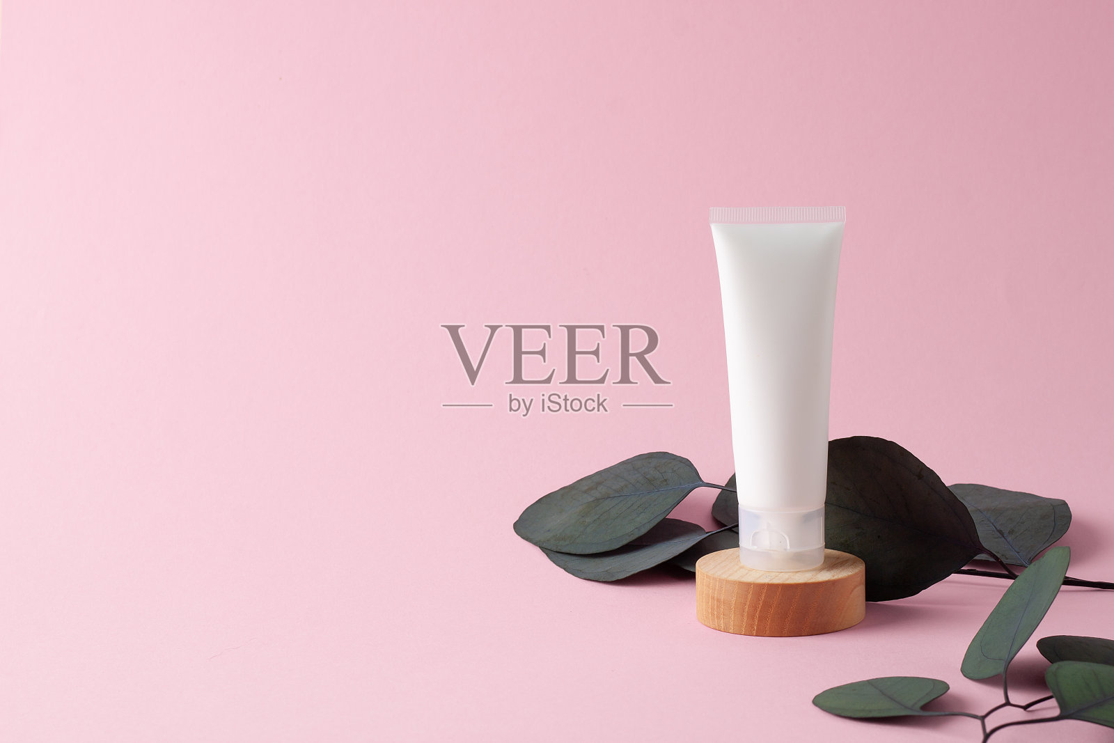 白色的化妆品管与桉树在木制讲台上粉红色的背景。关闭，复制空间。照片摄影图片