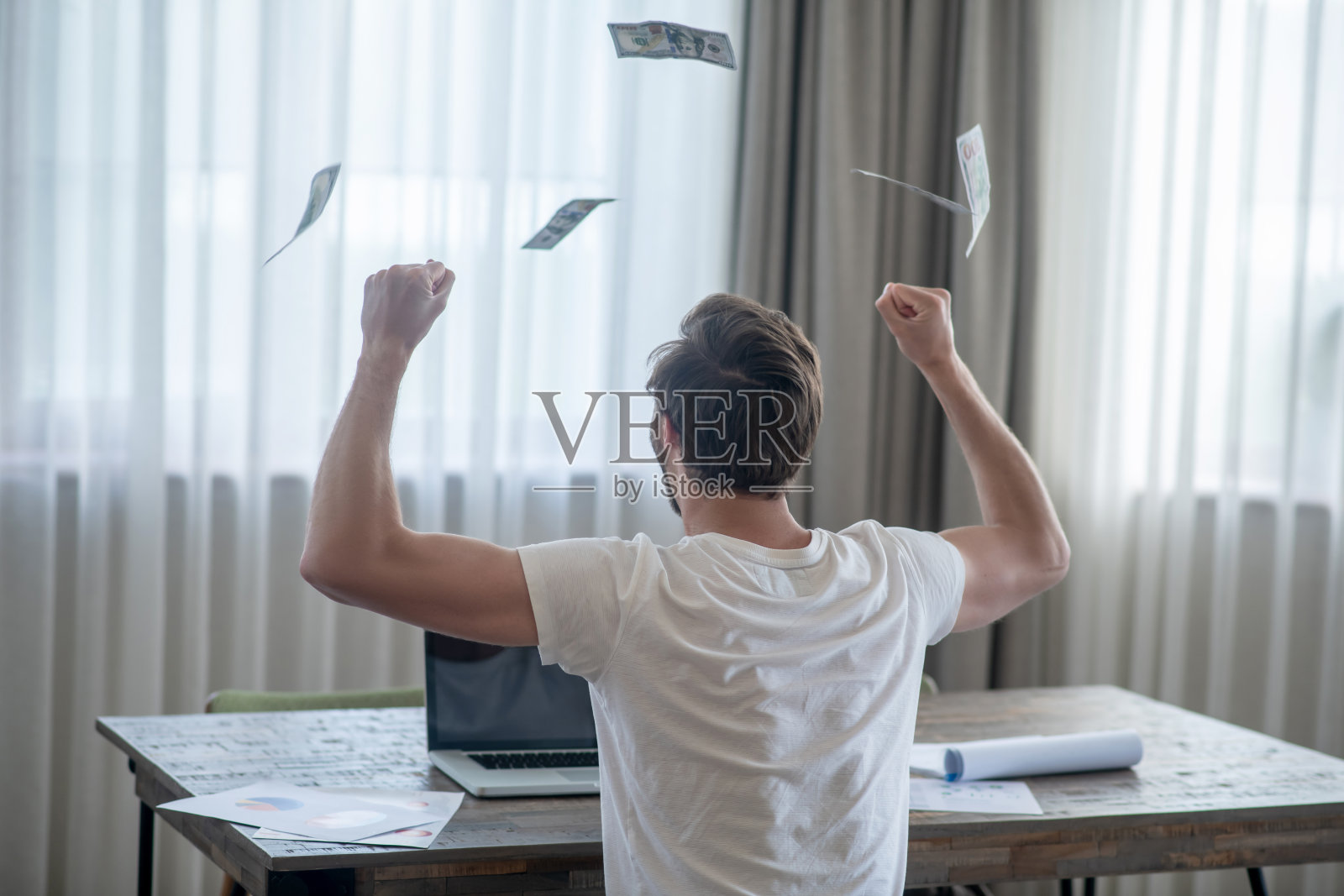 一名男子坐在笔记本电脑前，在达成一笔好交易后感到高兴照片摄影图片