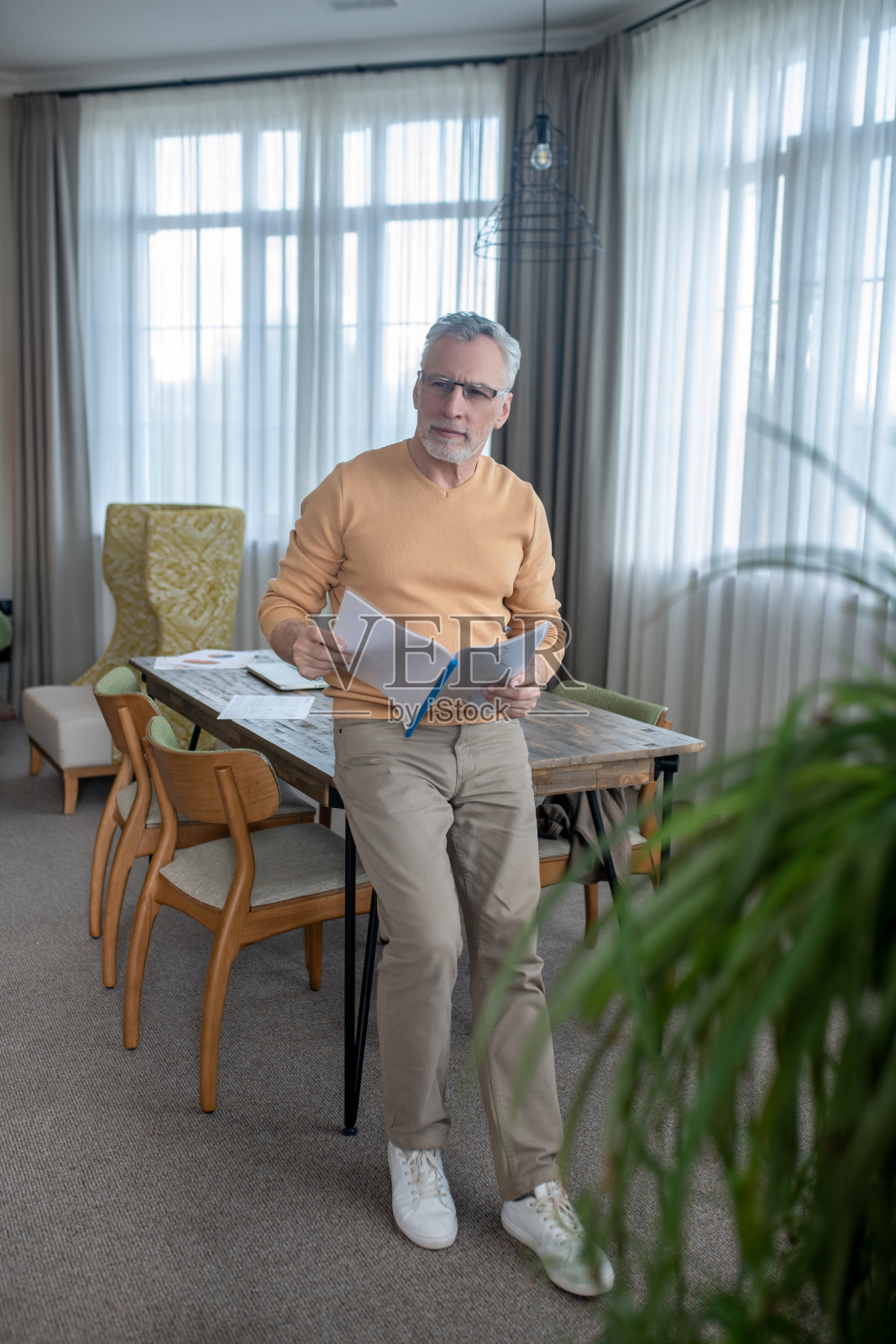 头发花白戴着眼镜的男人，在处理项目文件时看起来很忙照片摄影图片