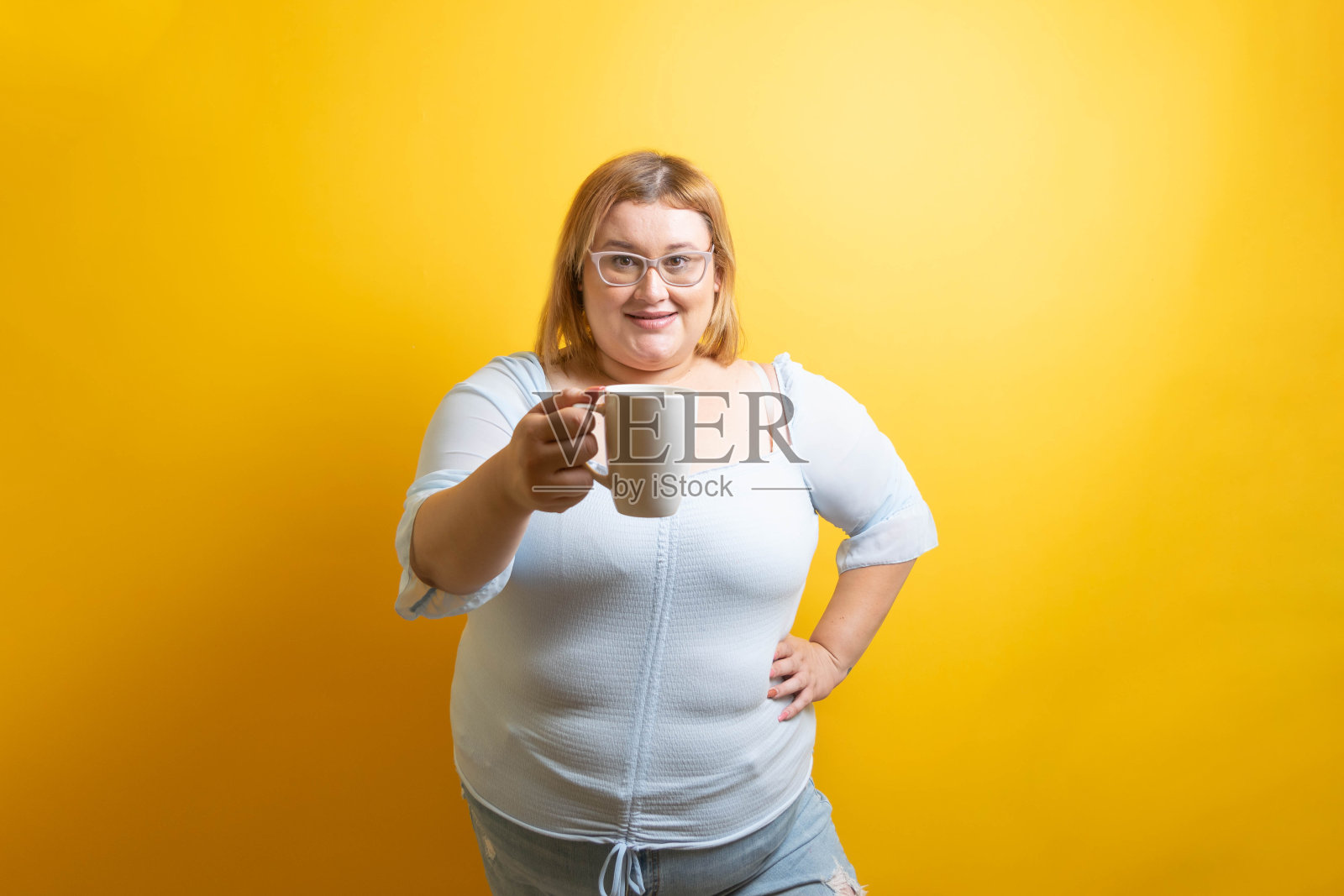 一个胖乎乎的白人年轻女人端着一杯咖啡。超重的人照片摄影图片