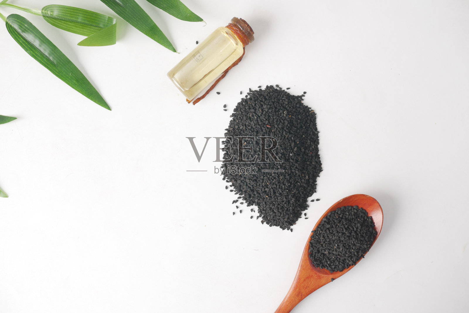 用勺子盛黑孜然，放油在桌上的罐子里。照片摄影图片