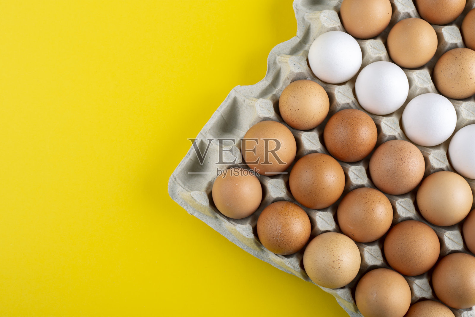 漂亮的大的农村新鲜鸡蛋在硬纸板蛋盒持有人与五颜六色的黄色背景。照片摄影图片