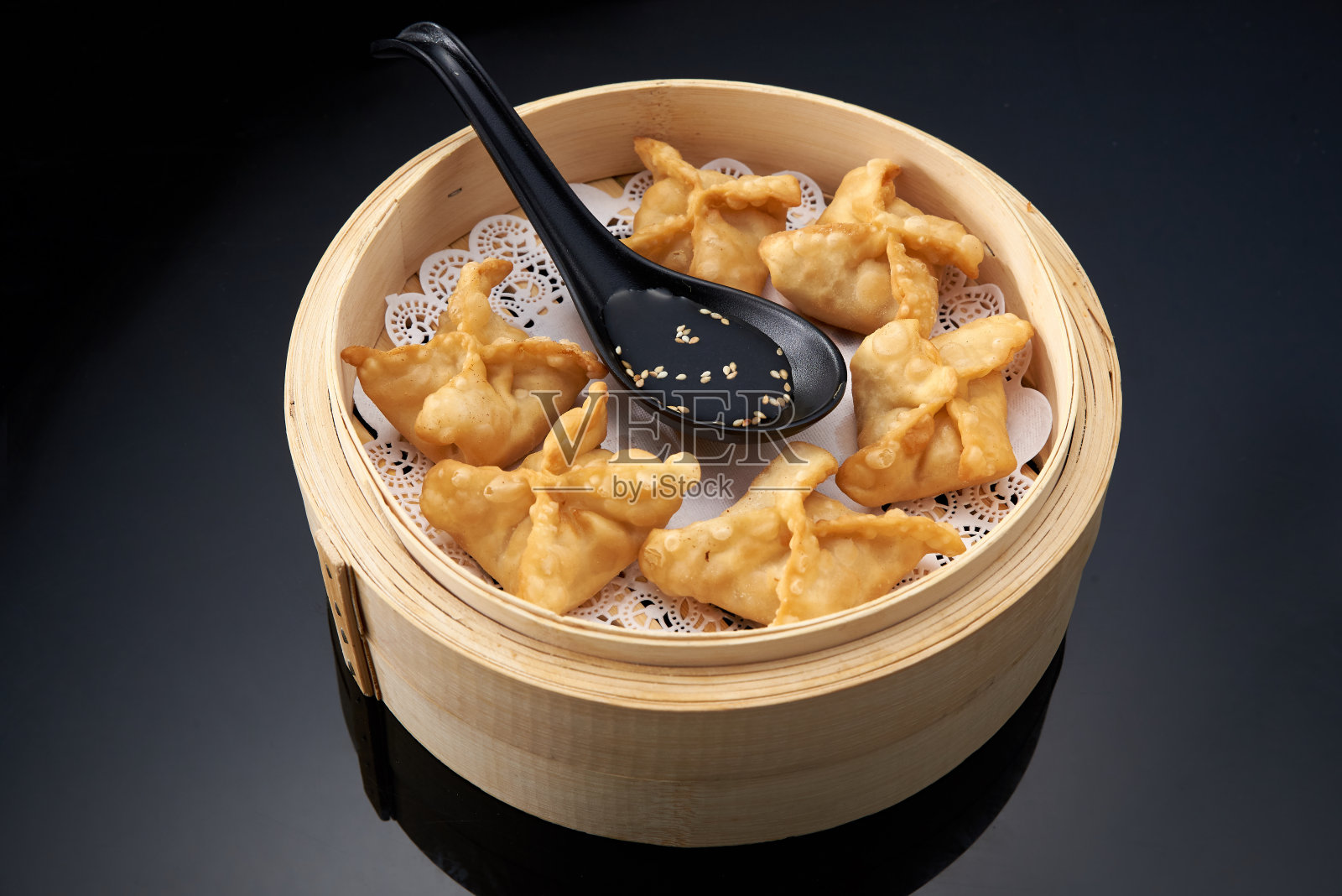 竹筒里的煎饺，背景是黑色的。照片摄影图片