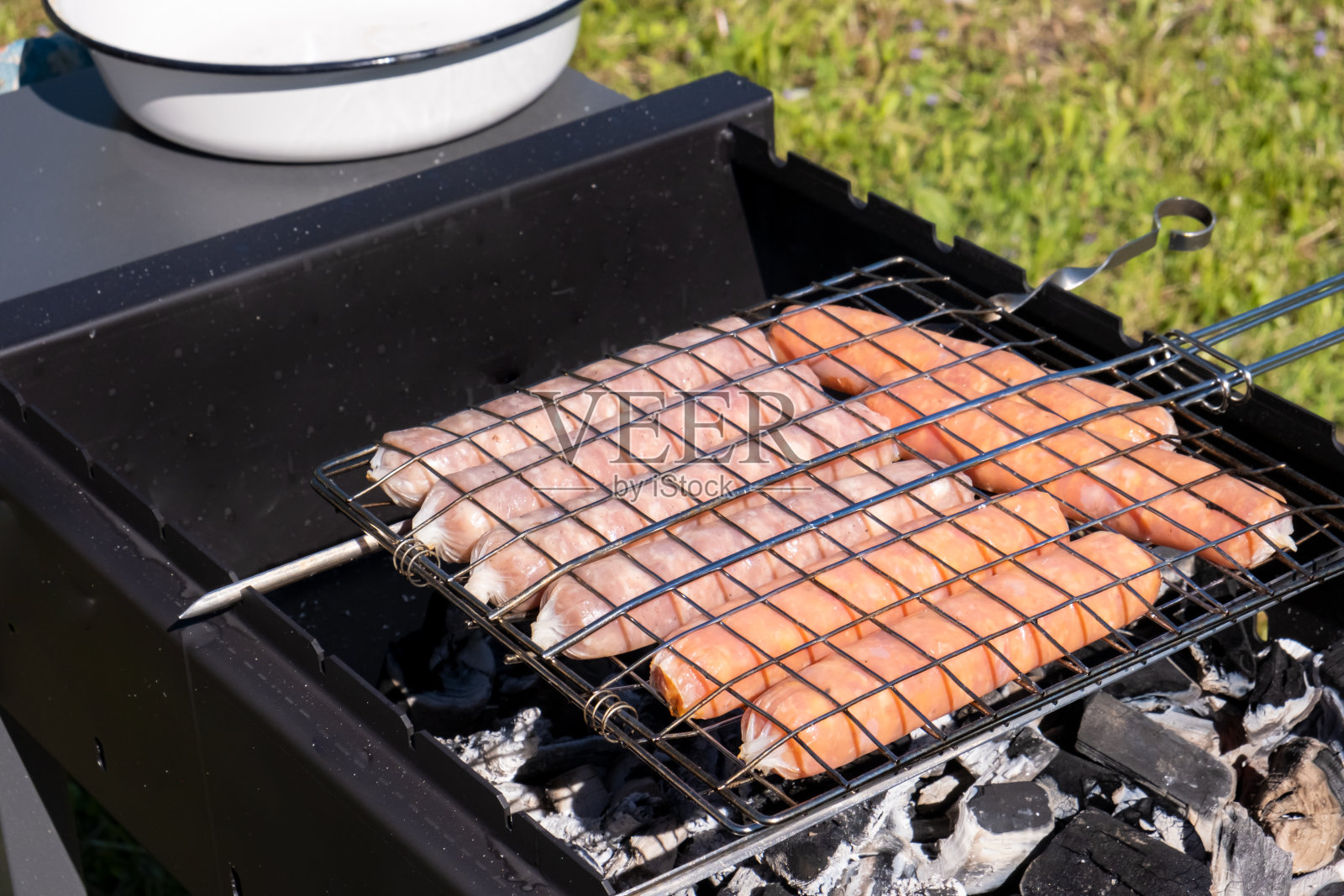 生香肠在木炭烤架上烤，夏季野餐在大自然中烧烤，烧烤烤架照片摄影图片