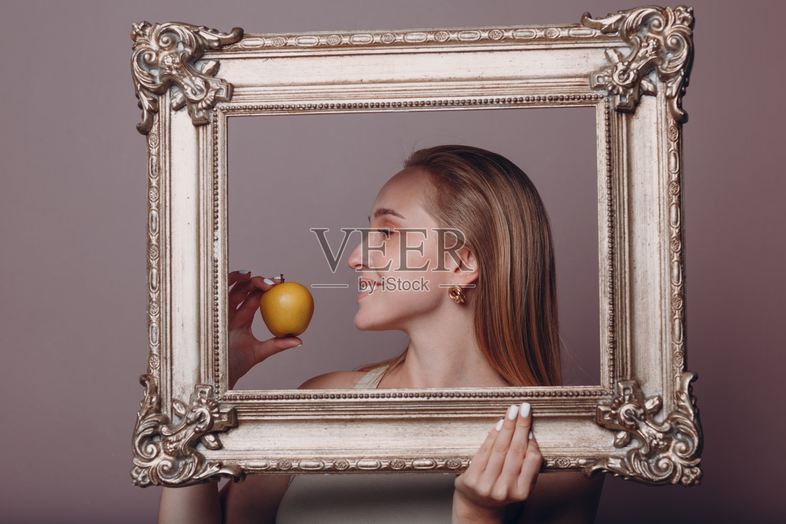 千禧年年轻女子金发手持镀金相框，脸部肖像照片摄影图片