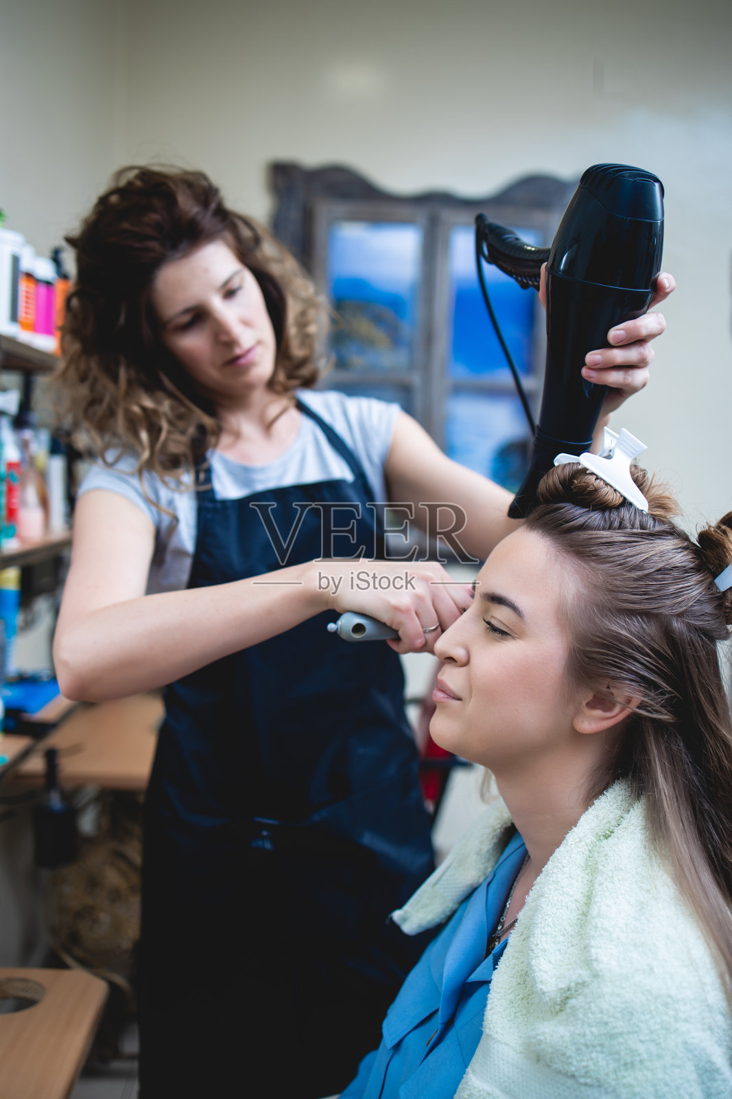 美发师在美发沙龙给一个年轻漂亮的女人梳头发。照片摄影图片