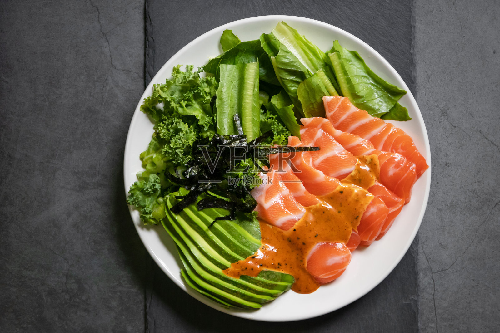 三文鱼沙拉，鳄梨，海带，日式蔬菜辣酱。在黑色表格背景上的俯视图。亚洲时尚食品。照片摄影图片