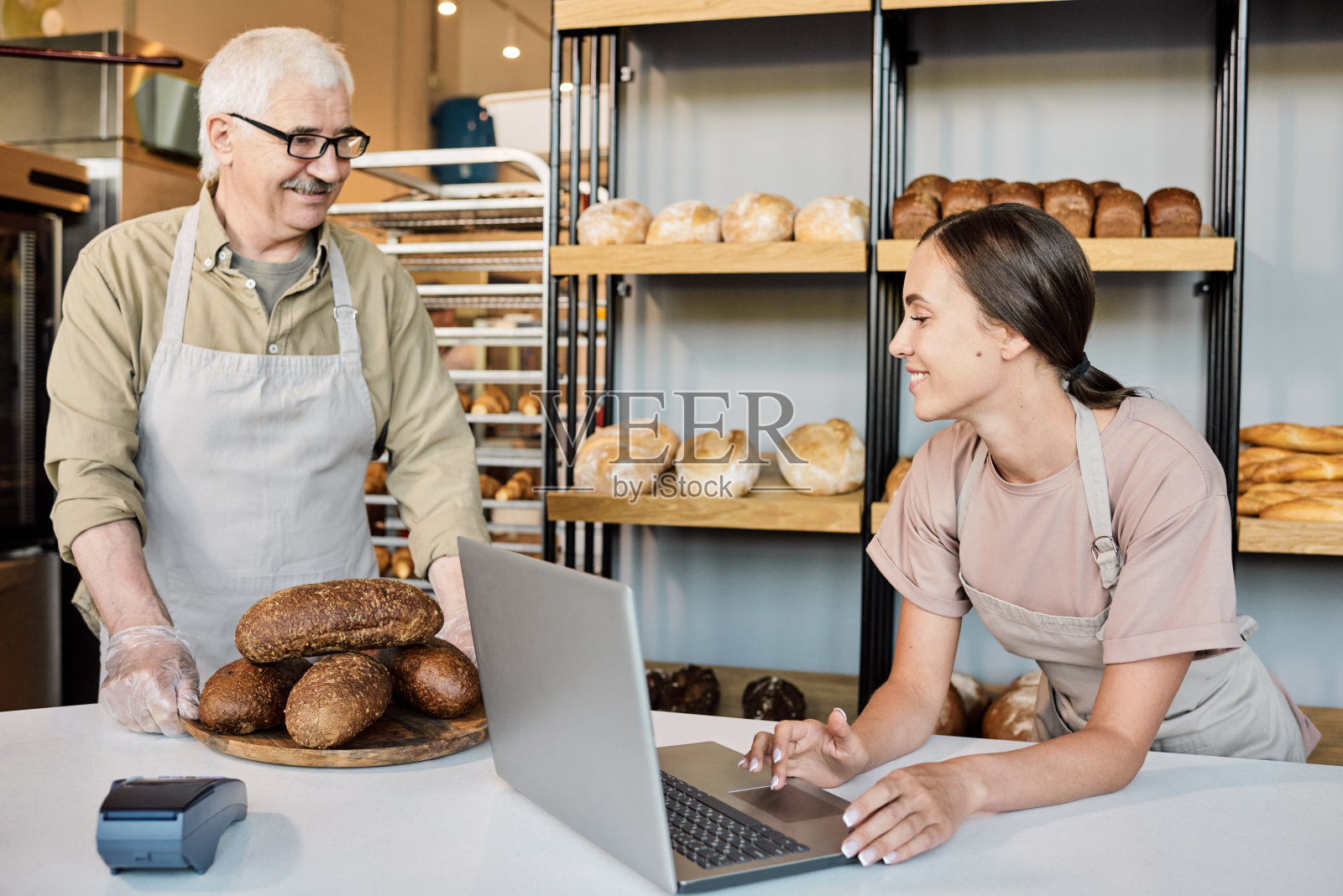 快乐的女人拿着笔记本电脑看着一堆新鲜的面包照片摄影图片