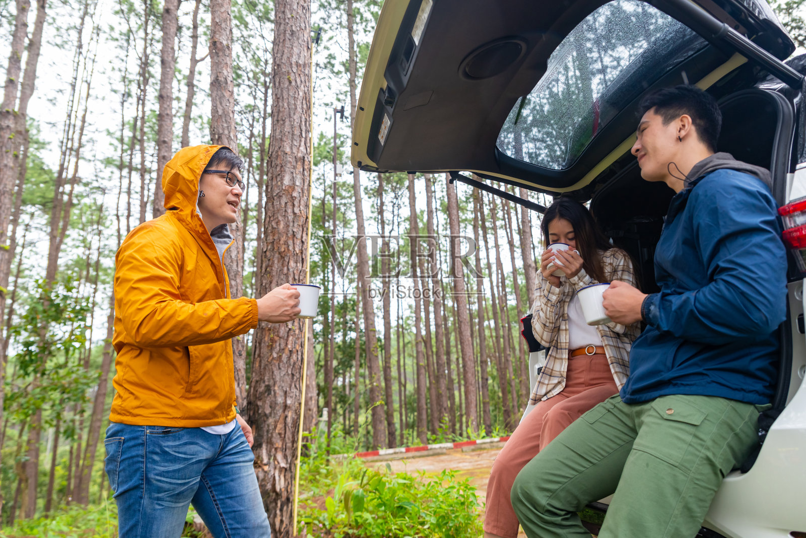 一群亚洲人朋友坐在敞篷的汽车后备箱里，一起喝咖啡照片摄影图片