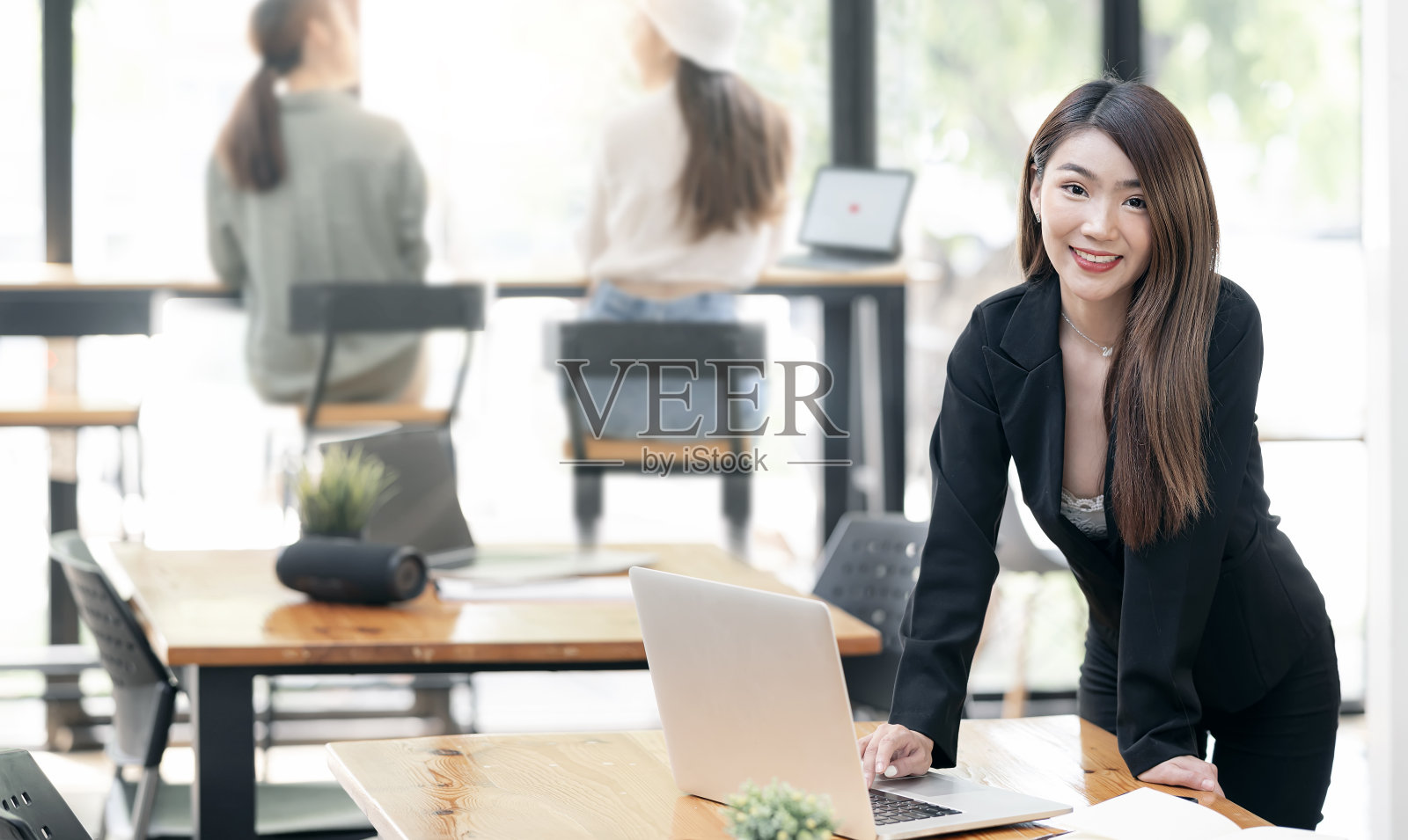 美丽的亚洲女商人站在她的办公桌和她的团队在办公室工作。照片摄影图片